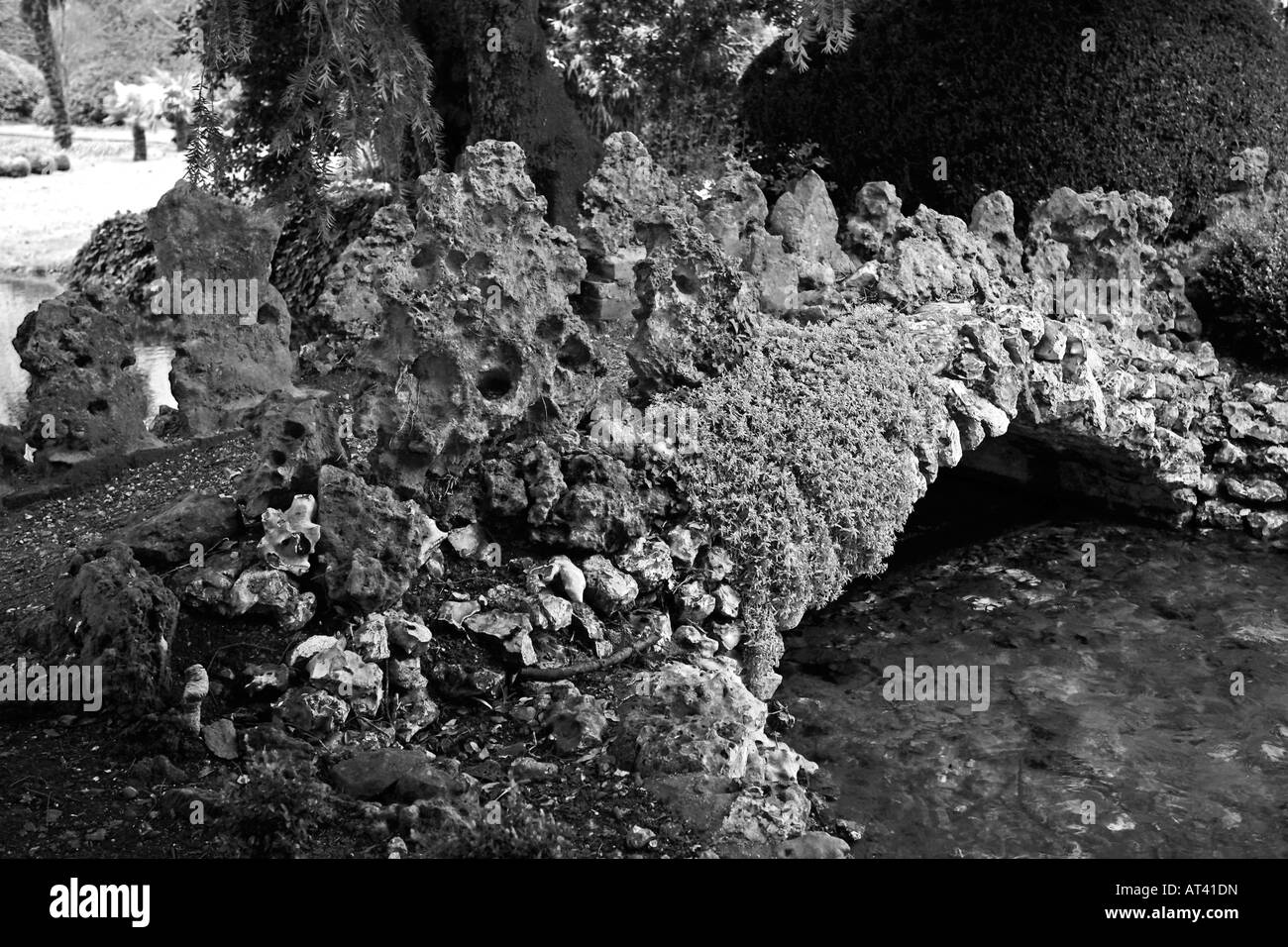 Immagine in bianco e nero di decorativi in pietra ponte sul torrente a West Dean Gardens, West Sussex, in Inghilterra, Regno Unito Foto Stock