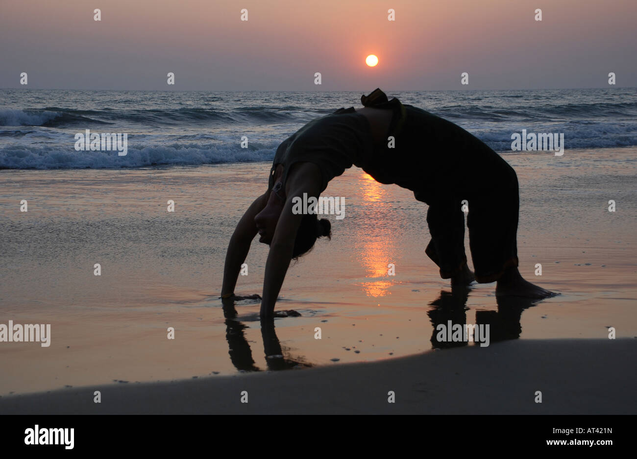 Donna facendo un po' di yoga schiena curva sulla spiaggia indiano Foto Stock