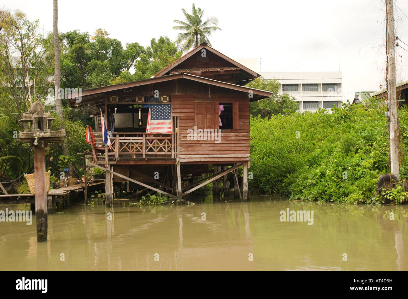 Una bandiera americana su una casa costruita su palafitte su un canale centrale di Bangkok in Thailandia Foto Stock