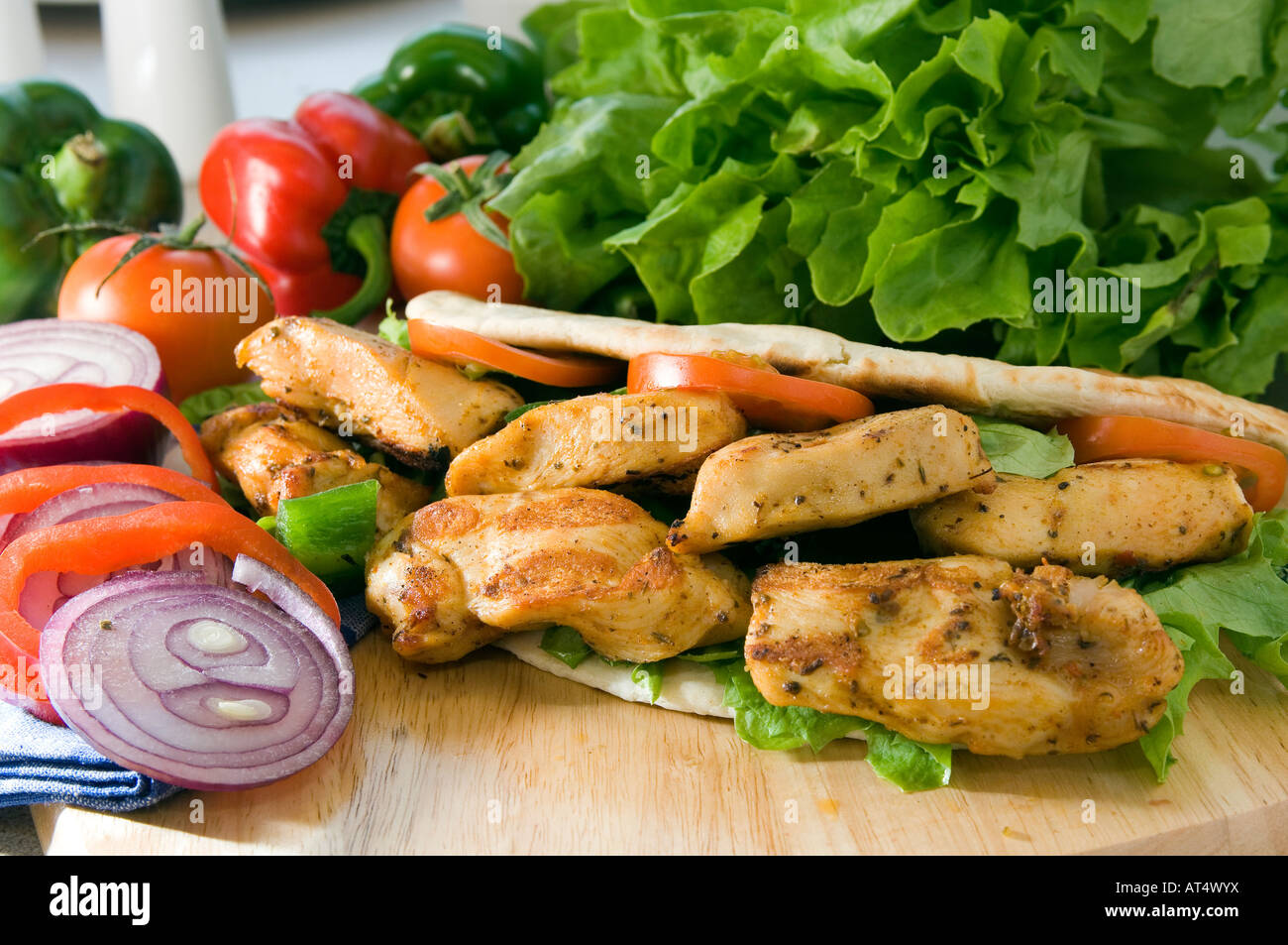 Un caldo fresco pollo shish kebab servito su un tagliere di legno in un pane pita con insalata Foto Stock