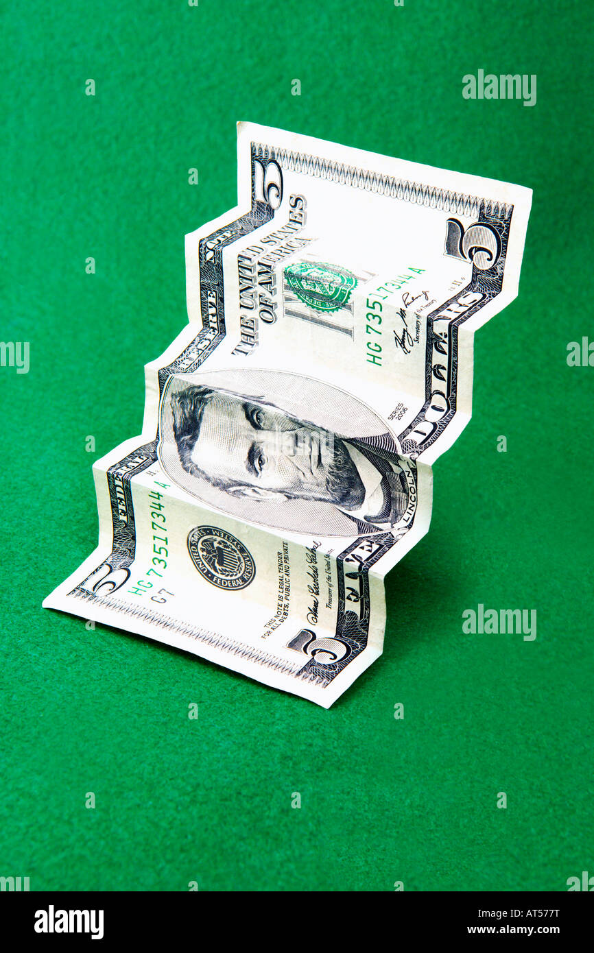 Cinque Dollari ripiegato per simulare le scale contro uno sfondo verde Foto Stock
