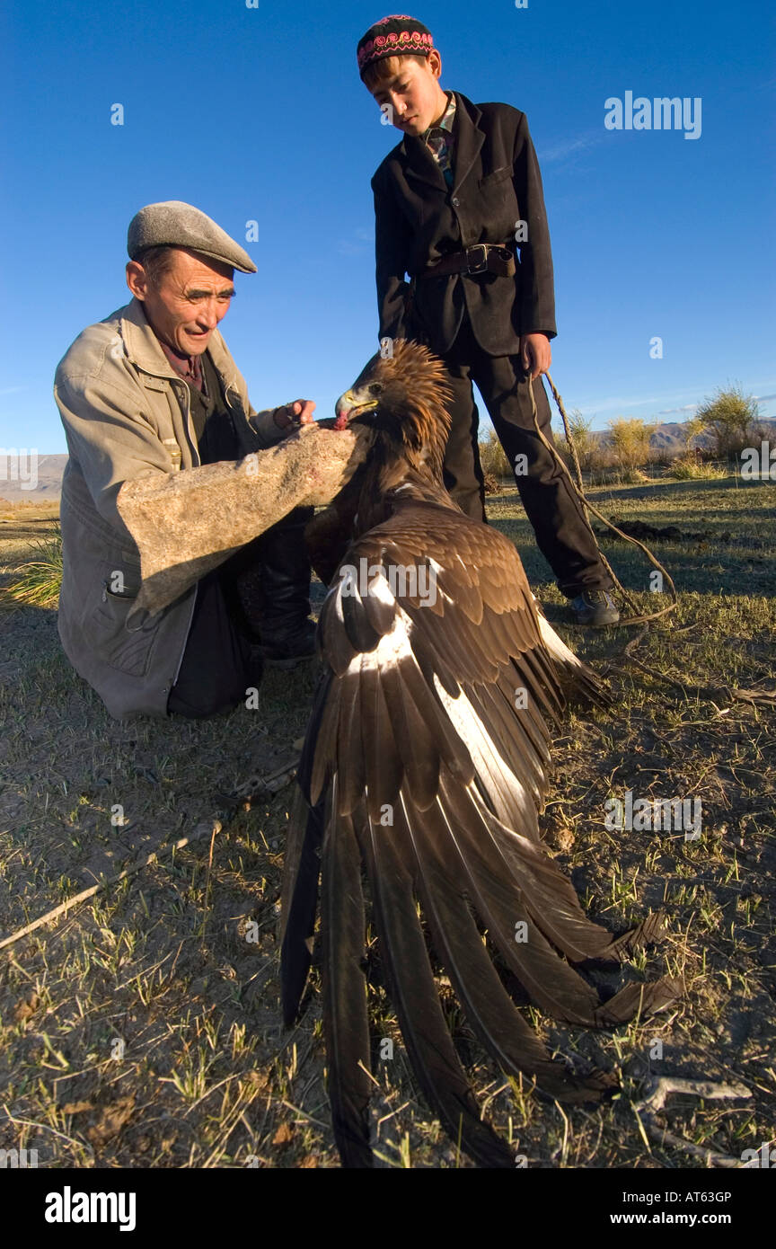 Un aquila hunter treni la sua aquila e insegna a suo figlio le antiche sport kazako di eagle caccia Bayan Olgi Mongolia Foto Stock