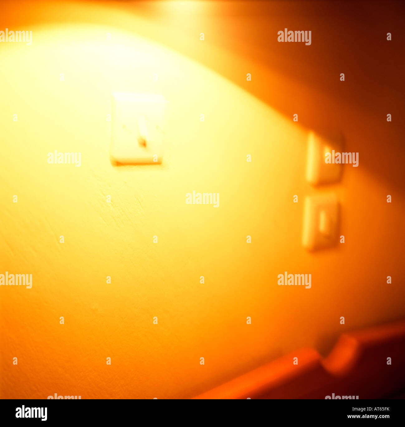 Abstract sfocati sfocato giallo luce incandescente sul muro con interruttori elettrici KATHY DEWITT Foto Stock