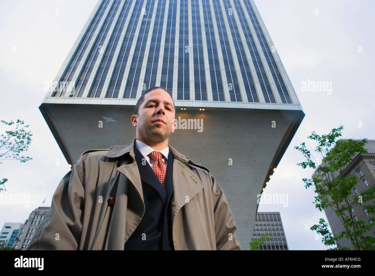 Ritratto di un imprenditore all'aperto in un ambiente urbano con un grande edificio che incombe sopra di lui Foto Stock