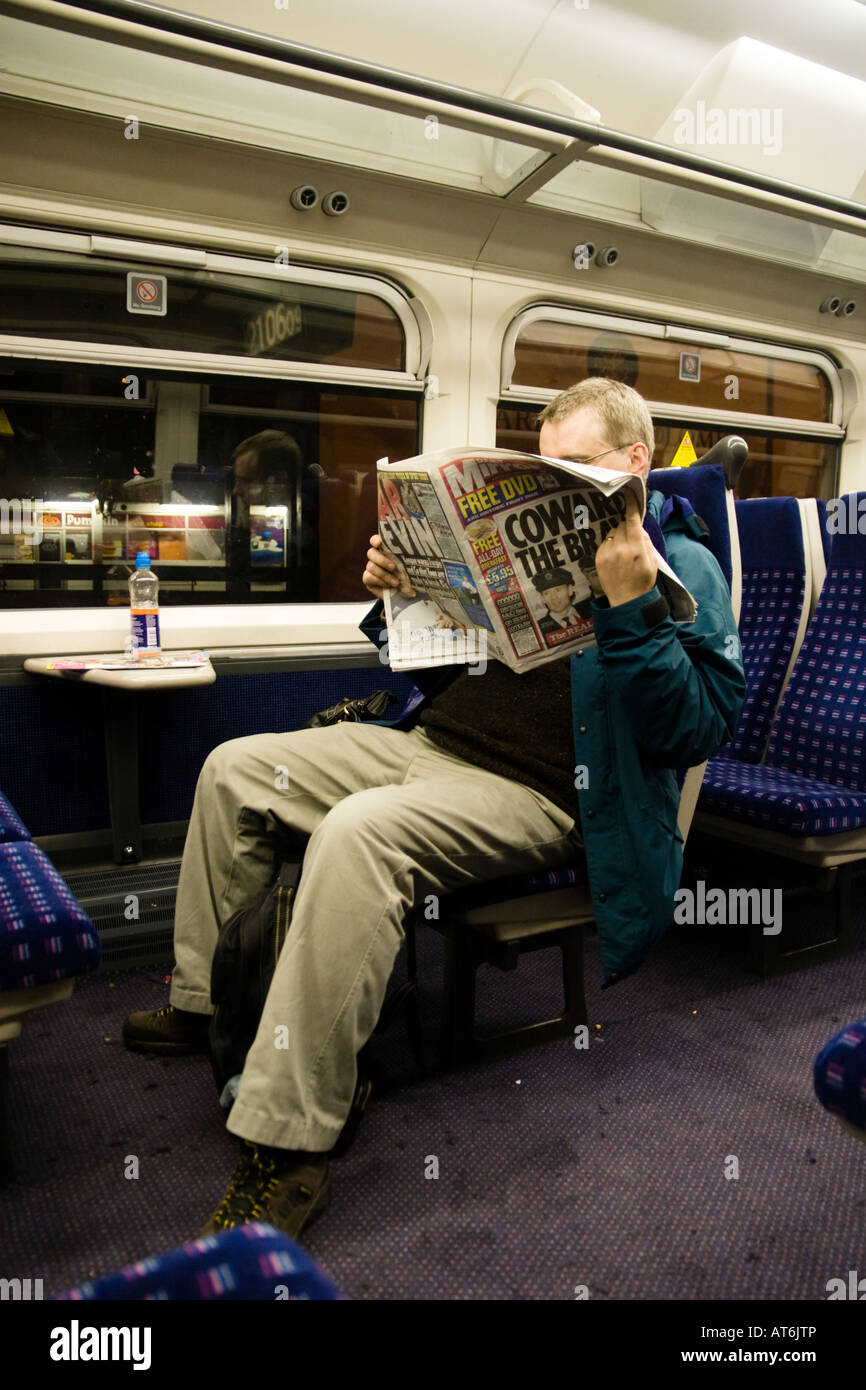 Uomo che legge il giornale in carrozza del treno di notte Foto Stock