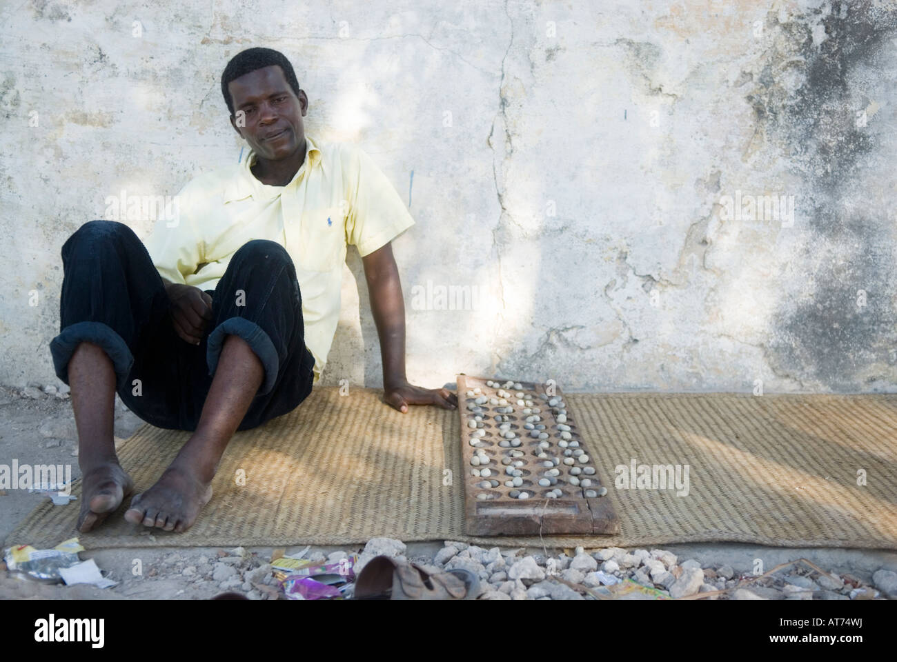Mozambico. Persona di sesso maschile in attesa di qualcuno a giocare il gioco della famiglia dei mancala. Makuti Town. Ilha de Mozambico. Foto Stock