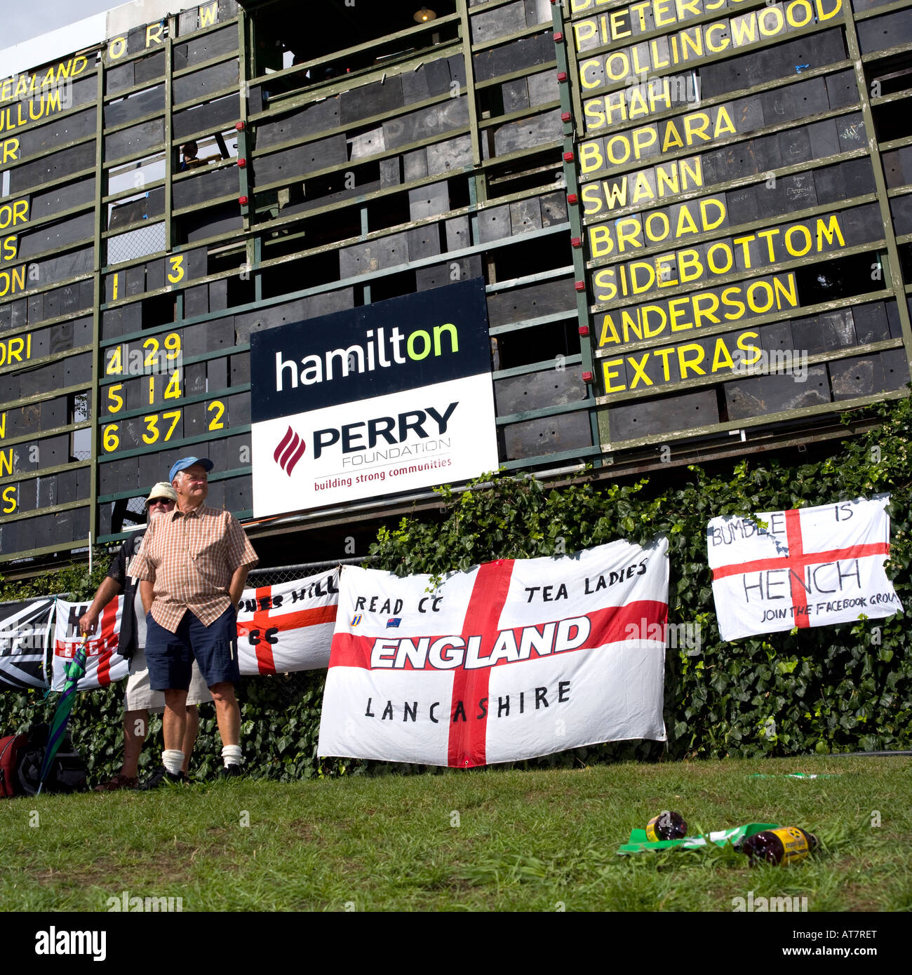 Due uomini anziani sulla collina di erba sotto il cricket scoreboard con bandiere inglese Foto Stock