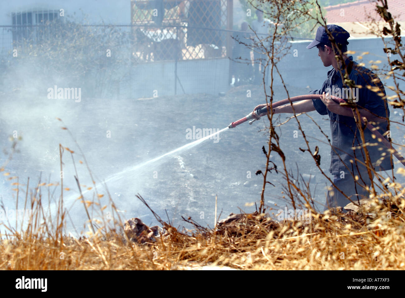 Un membro del GRECO vigili del fuoco i tubi boccole senza fiamma vicino a un sobborgo di Atene Foto Stock