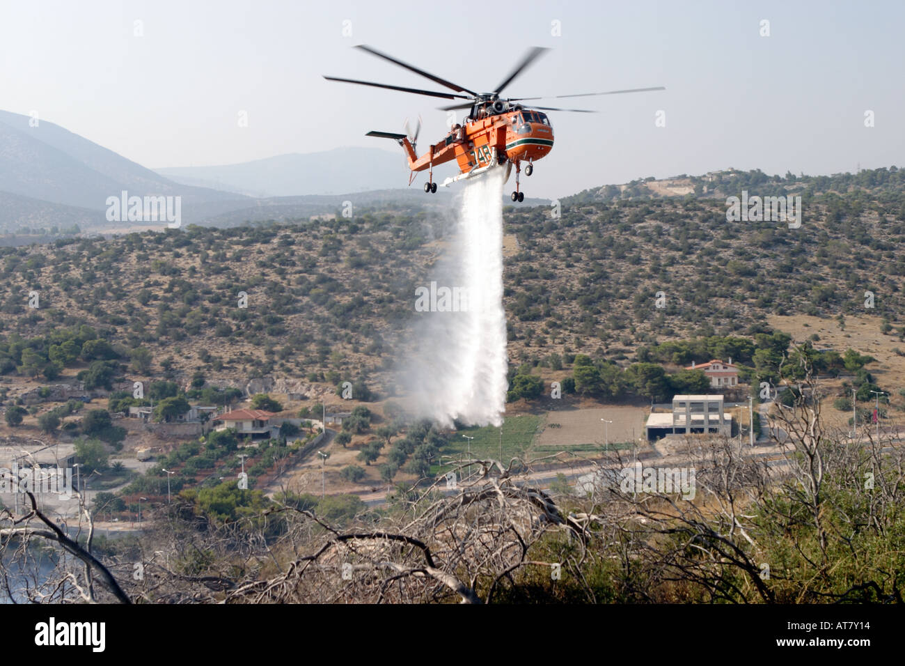 Erickson Air Crane fire servizio elicottero passa sopra un incendio di foresta in un sobborgo di Atene e comincia la sua goccia d'acqua Foto Stock