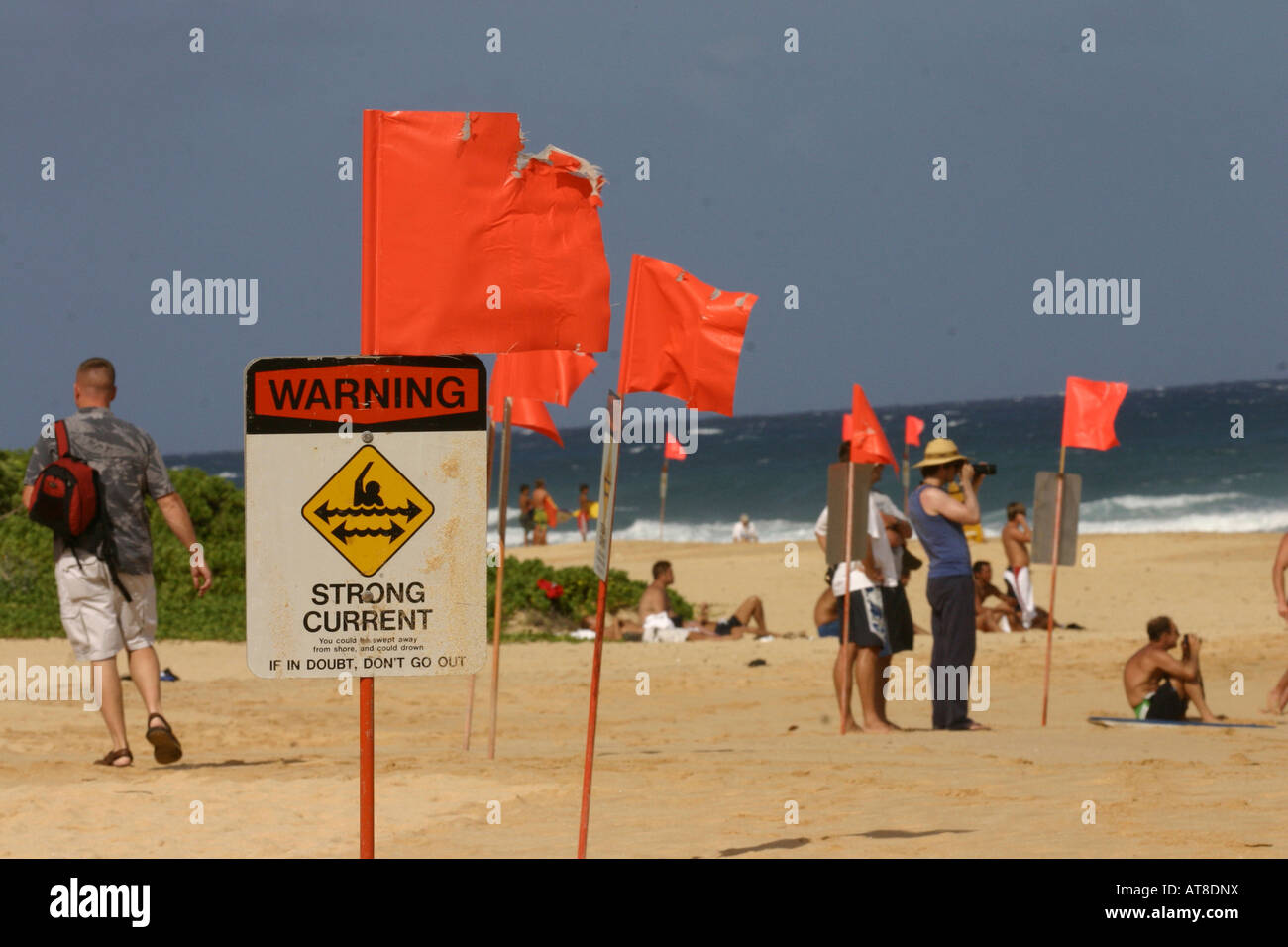 Gli spettatori in background obbedire surf cartelli di avvertimento alla spiaggia sabbiosa. Foto Stock