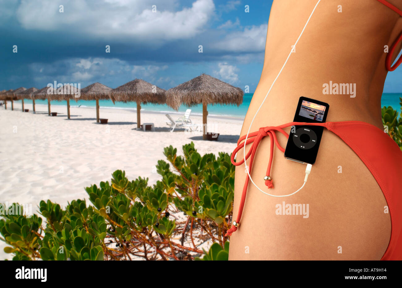 Donna con iPod nano nascosto in rosso cintura bikini in ambiente tropicale Foto Stock