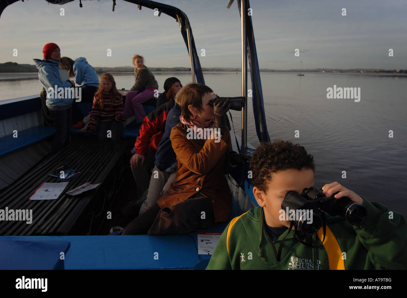 I bambini per il bird watching con il cannocchiale su una barca sull'estuario in Topsham, Devon su una molla pomeriggio. Foto Stock