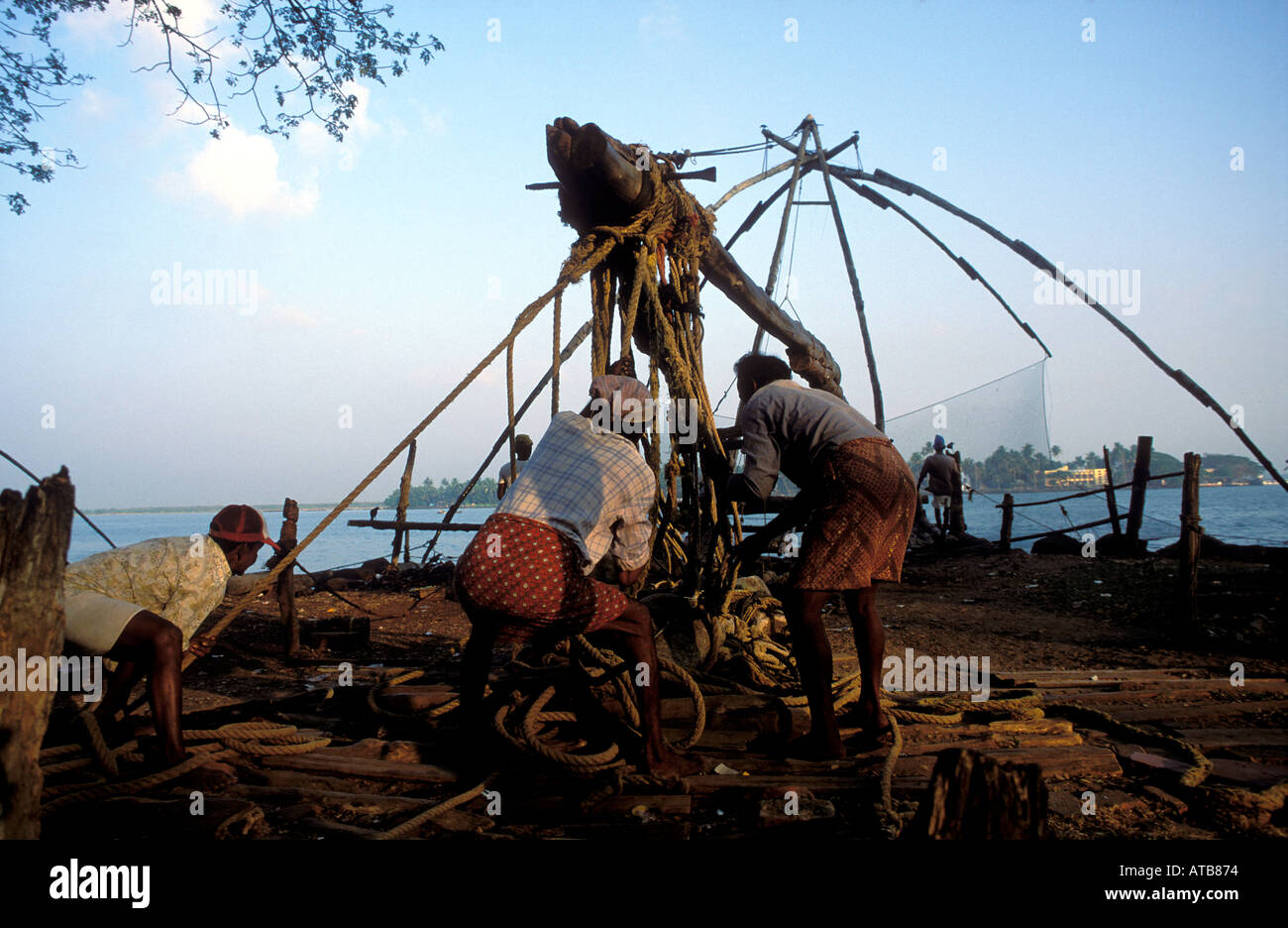 India Kerala cochin pescatori tirando i cinesi reti da pesca per ottenere pesci Fort Cochin Foto Stock