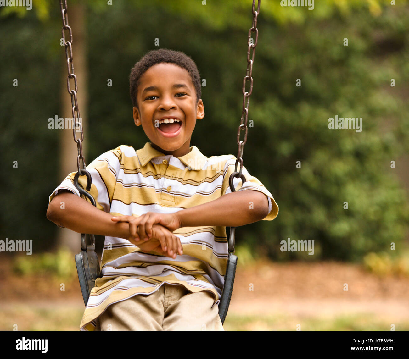 Sorridenti ragazzo su altalena nel parco giochi per bambini Foto Stock