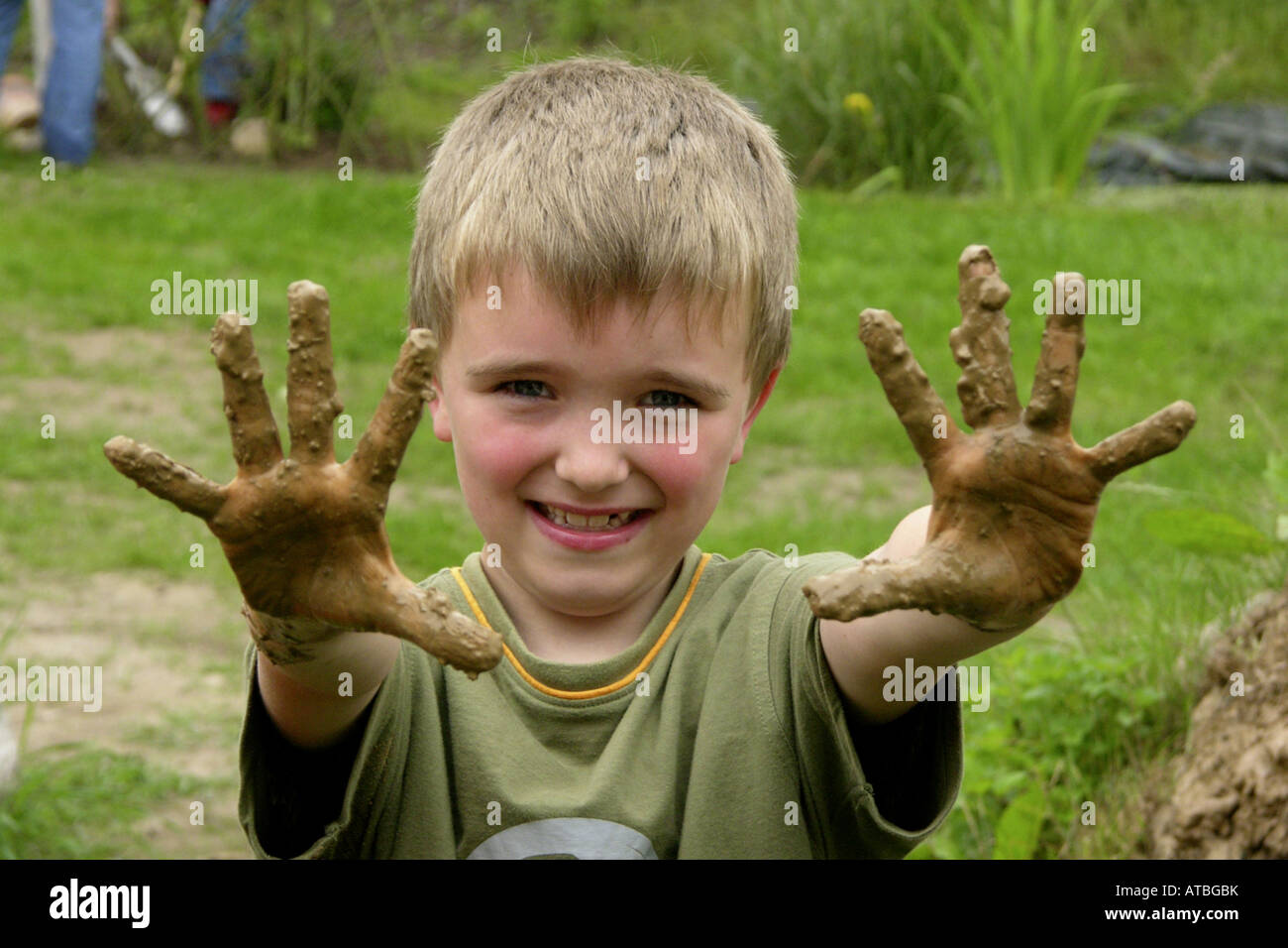 Figlio di una scuola primaria è costruire un forno fuori brickearth che mostra le mani sporche Foto Stock