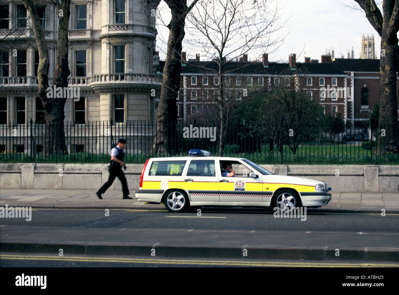 La polizia auto parcheggiate in westminster con il funzionario armati camminando lungo il lato Foto Stock