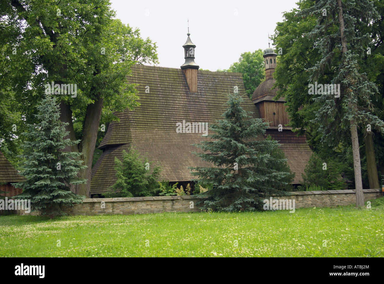 Vista della chiesa in legno - apostoli la chiesa di San Filippo e San Giacomo che mostra parco con alberi in primo piano. Foto Stock