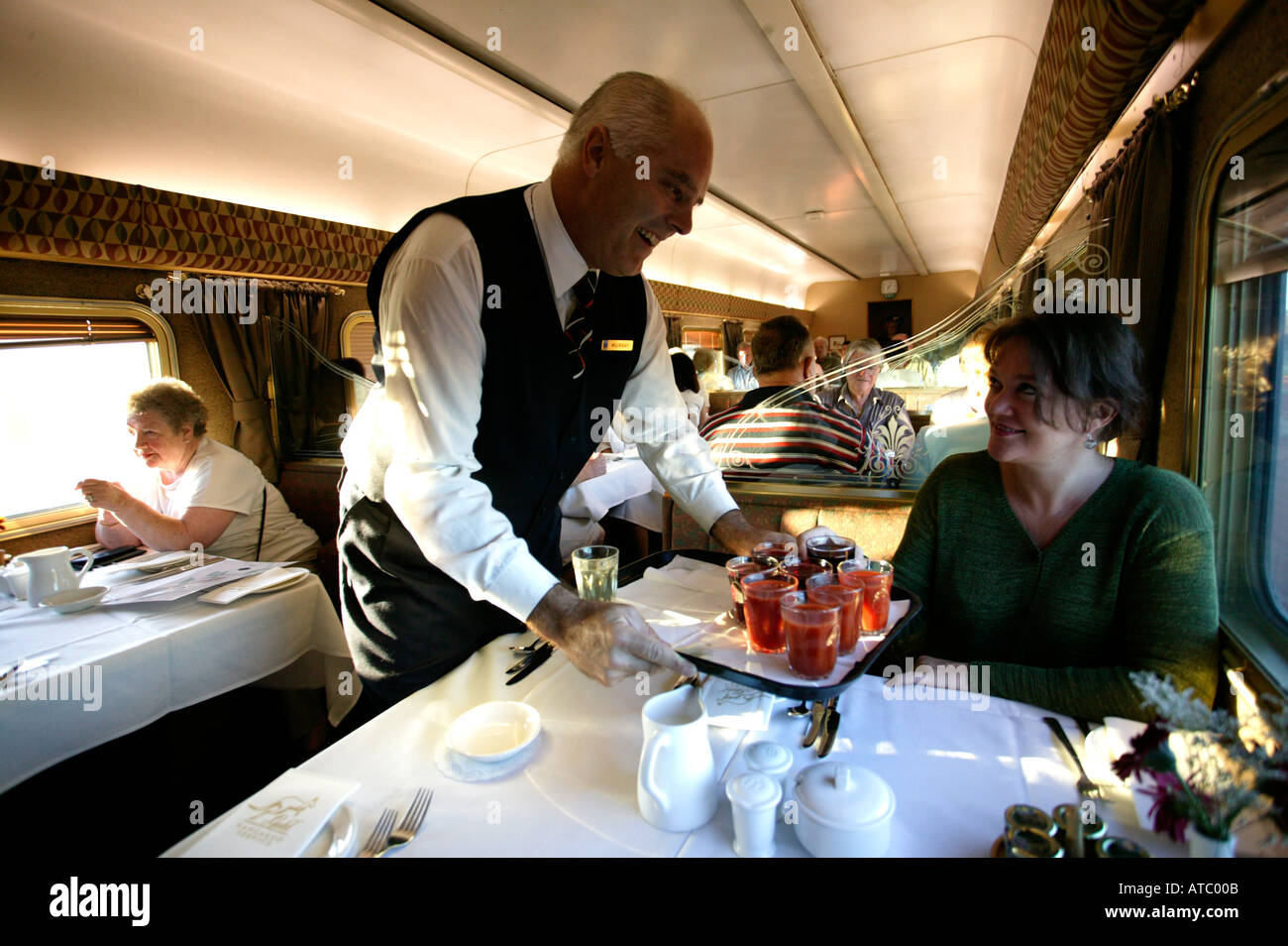 Una donna passeggero viene servito il tè da un ben vestiti cameriere in prima classe carrello pranzo del treno Ghan in Australia Foto Stock