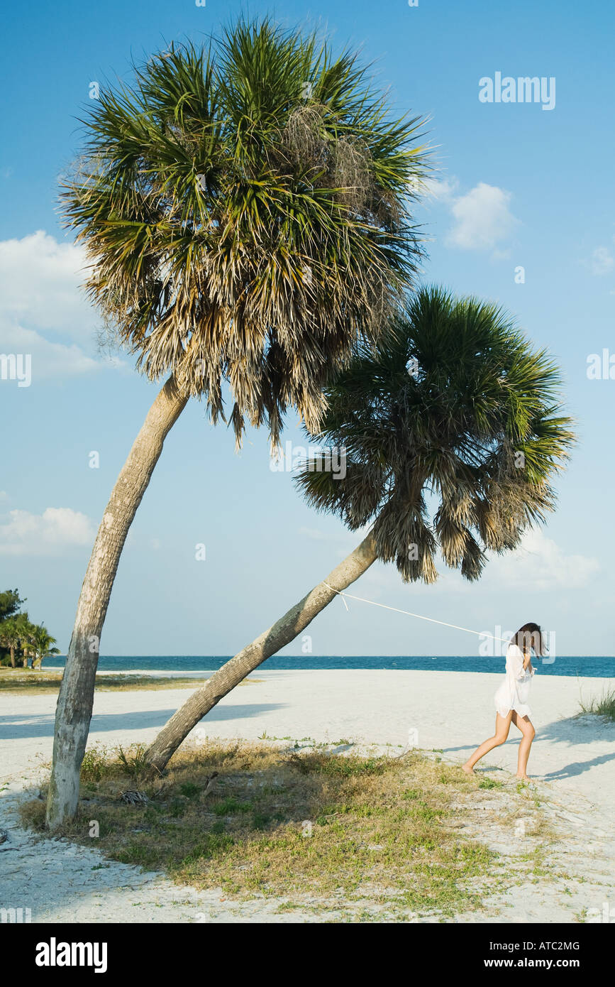 Donna tirando Palm tree con fune Foto Stock