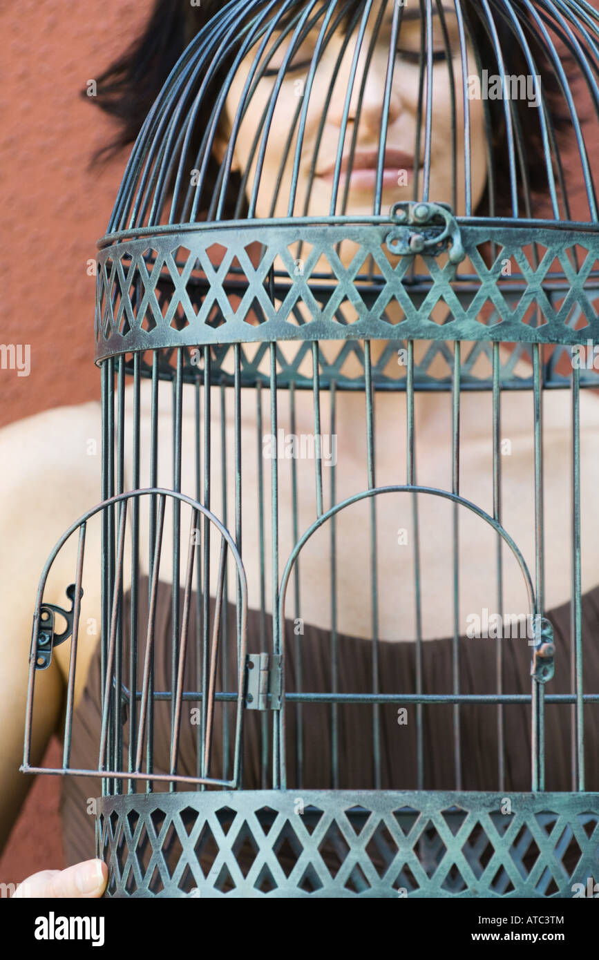 Donna che mantiene birdcage vuota con lo sportello aperto a occhi chiusi, ritagliato Foto Stock