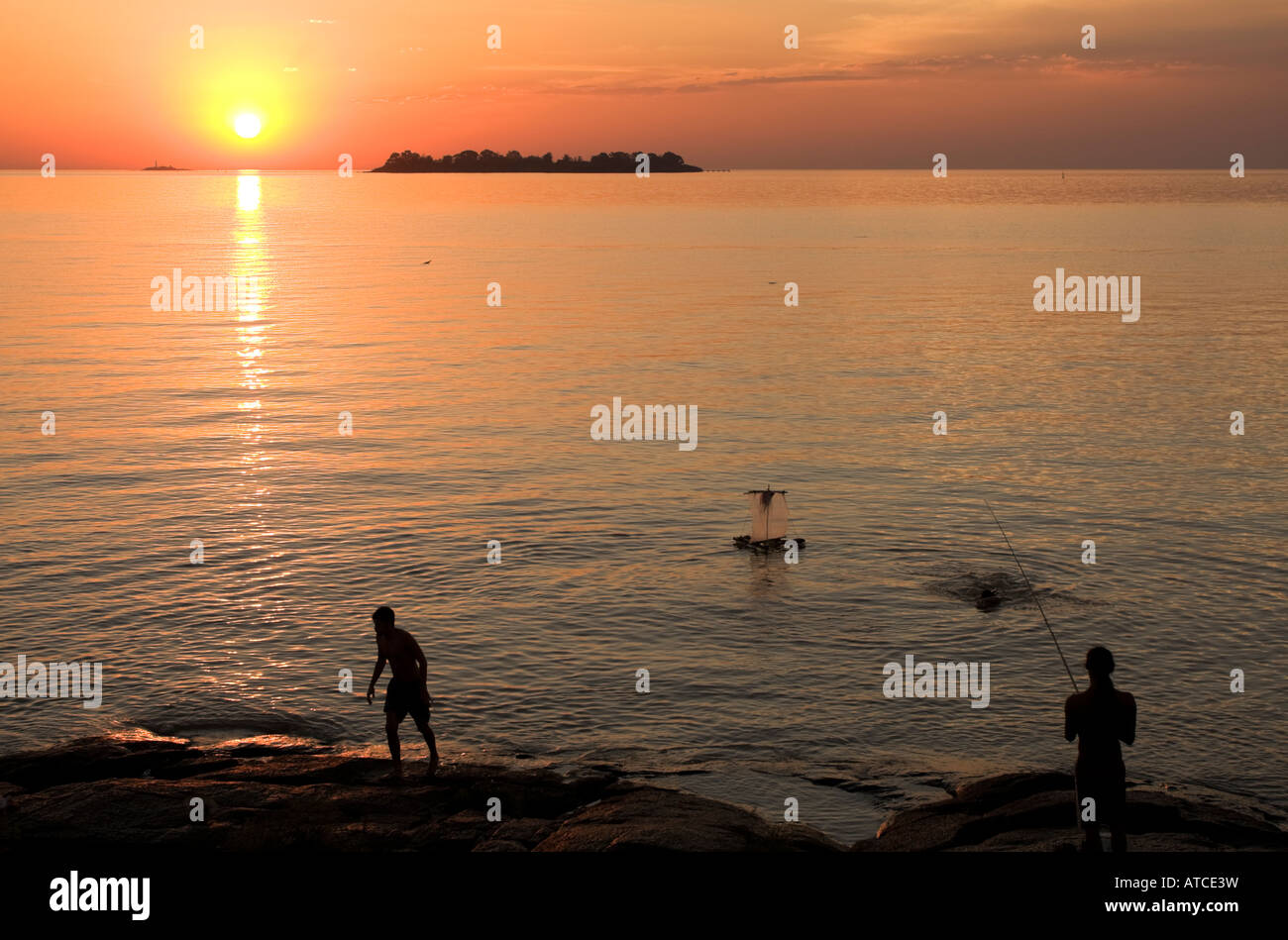 Due giovani uomini sulla riva del Río de la Plata in Coloñia del Sacramento Uruguay stagliano da sole di setting Foto Stock