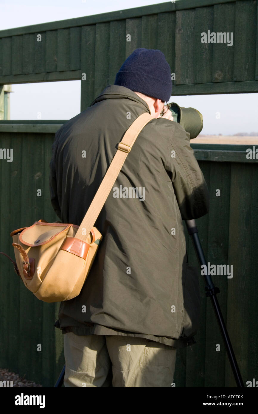 Osservazione degli uccelli costieri, vestito di verde, con portata da nascondere a Sandside, Marshside RSPB Riserva, Southport, Merseyside, Regno Unito Foto Stock