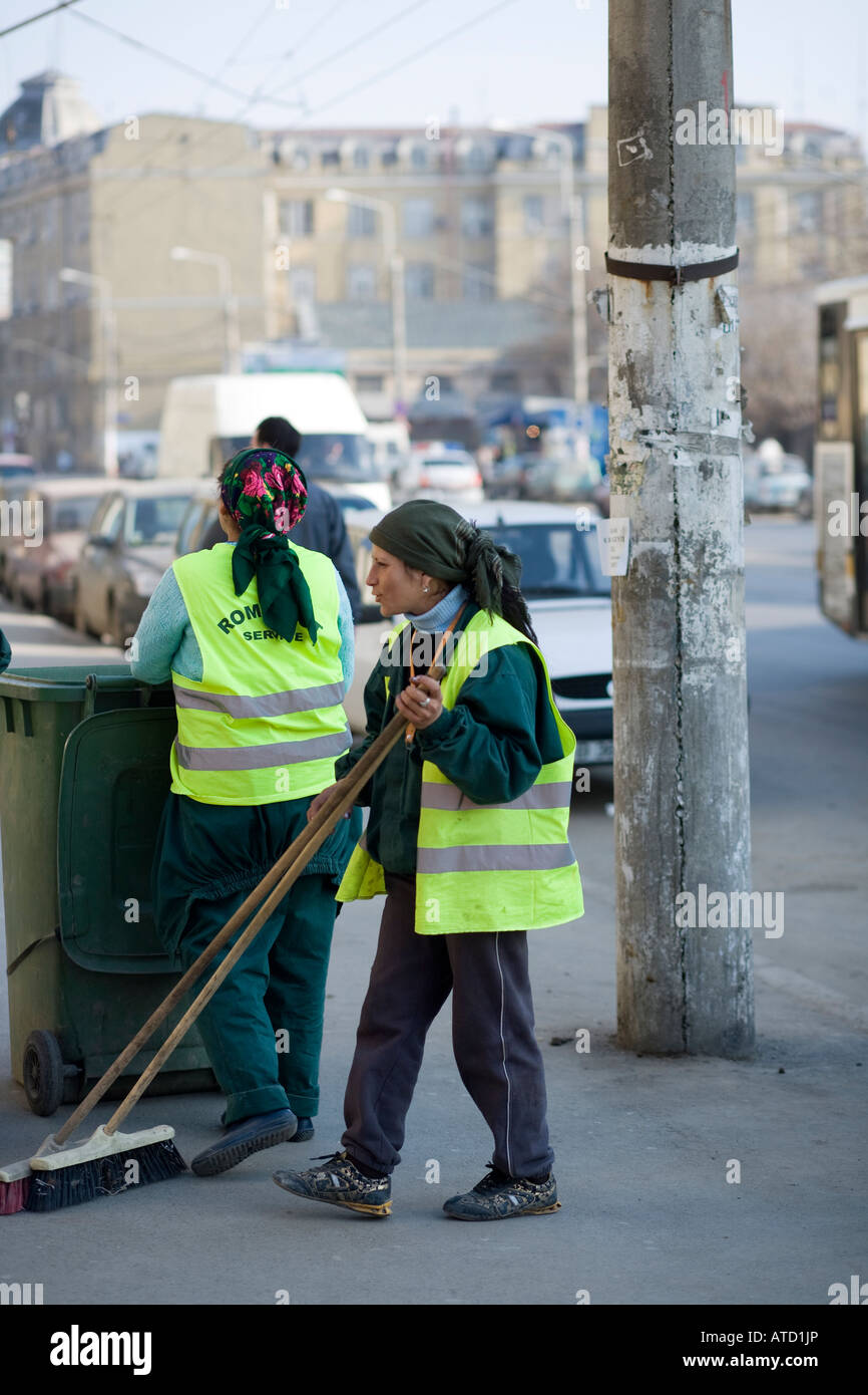 Rifiutare-collettori sulla strada fra le auto takeing lontano la spazzatura e utensili per la pulizia Foto Stock