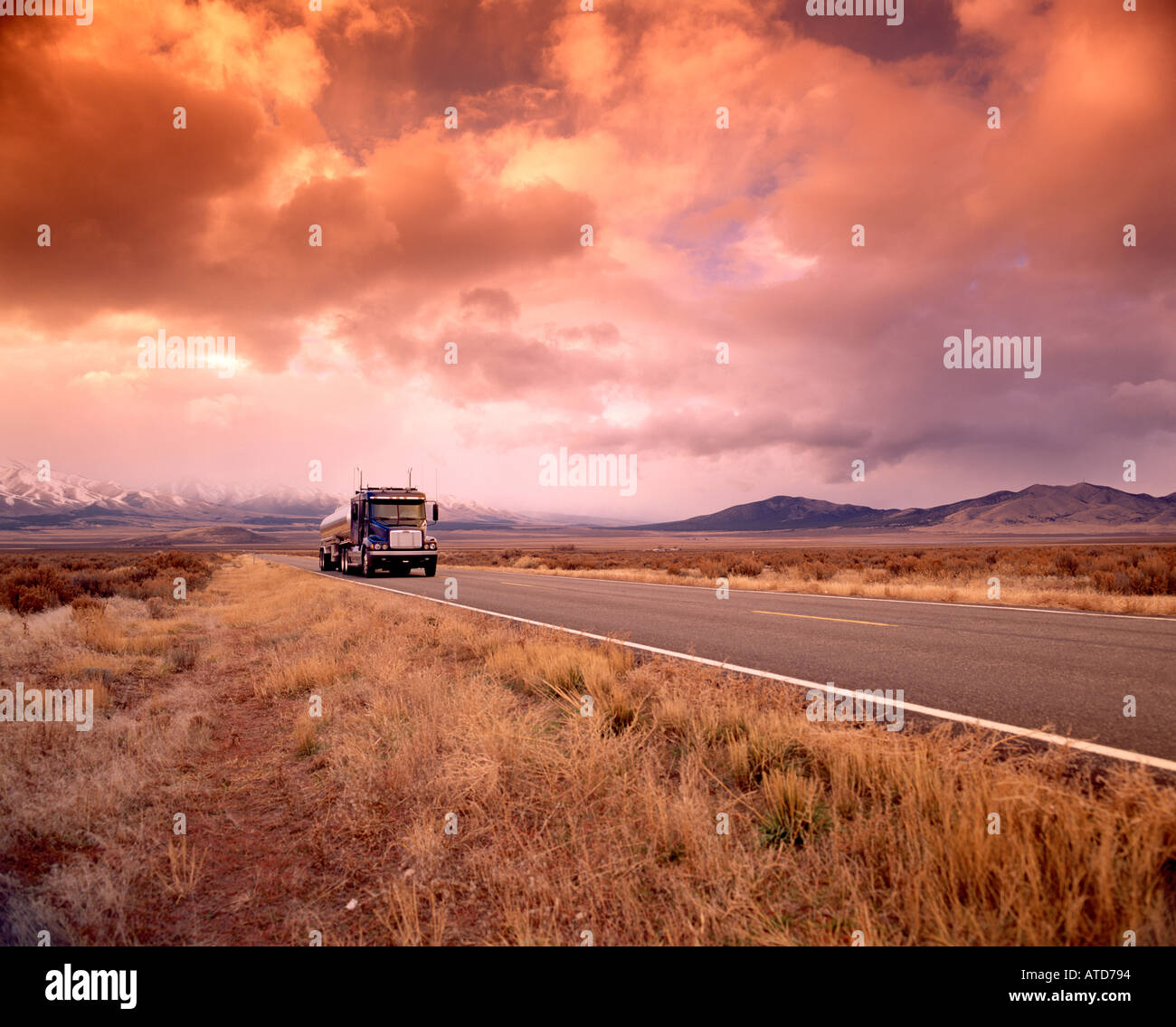 Un trattore roulotte carrello diciotto wheeler o semi viaggia attraverso un paesaggio arido sotto una coltre di nubi Foto Stock
