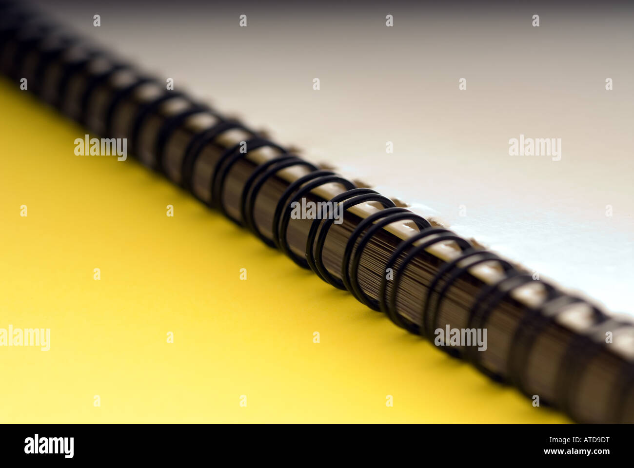 Macro di un bianco anello a spirale documento rilegato su sfondo giallo Foto Stock