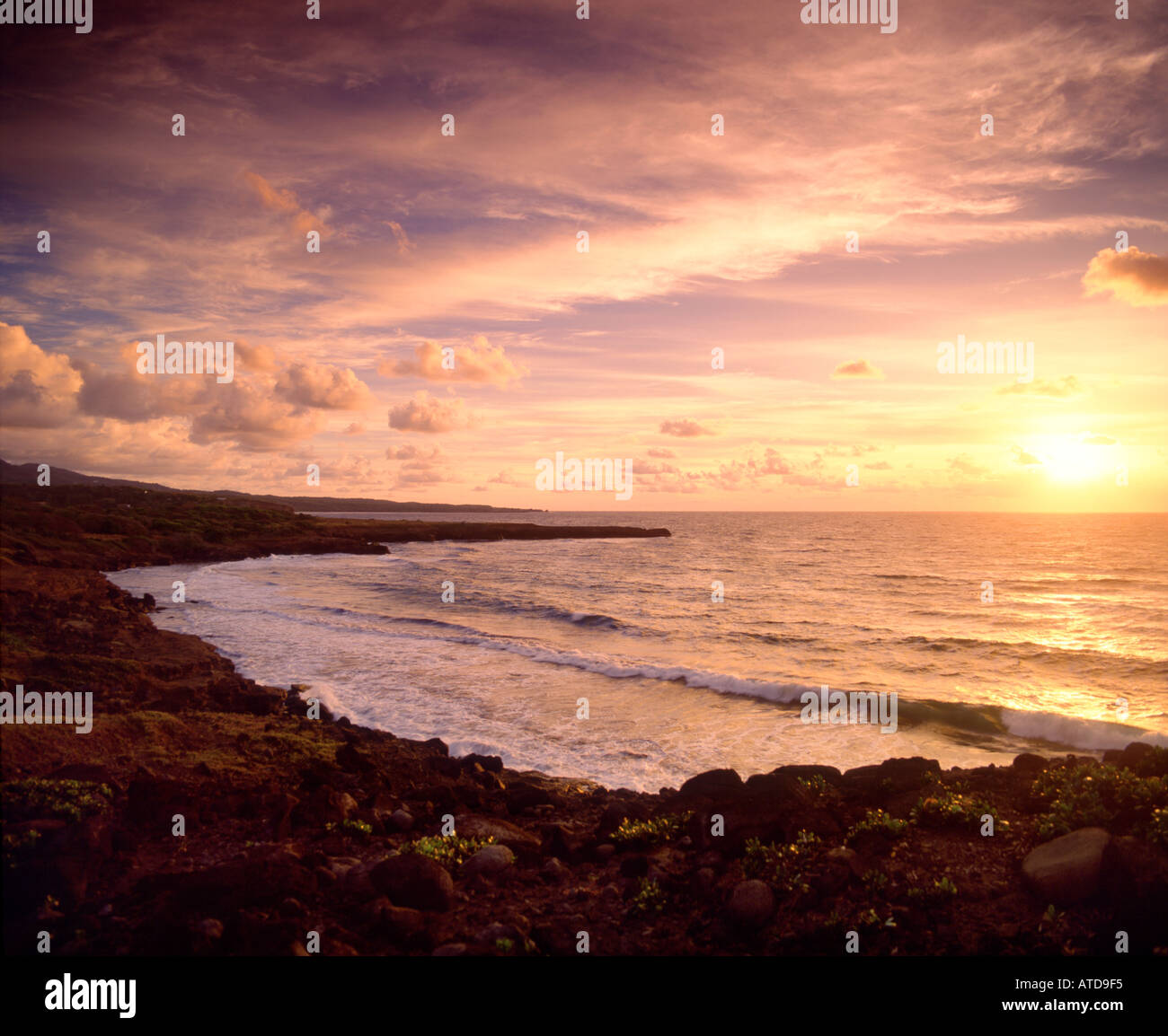 Giro delle onde della costa rocciosa di una spiaggia dell'isola caraibica di Grenada al tramonto Foto Stock