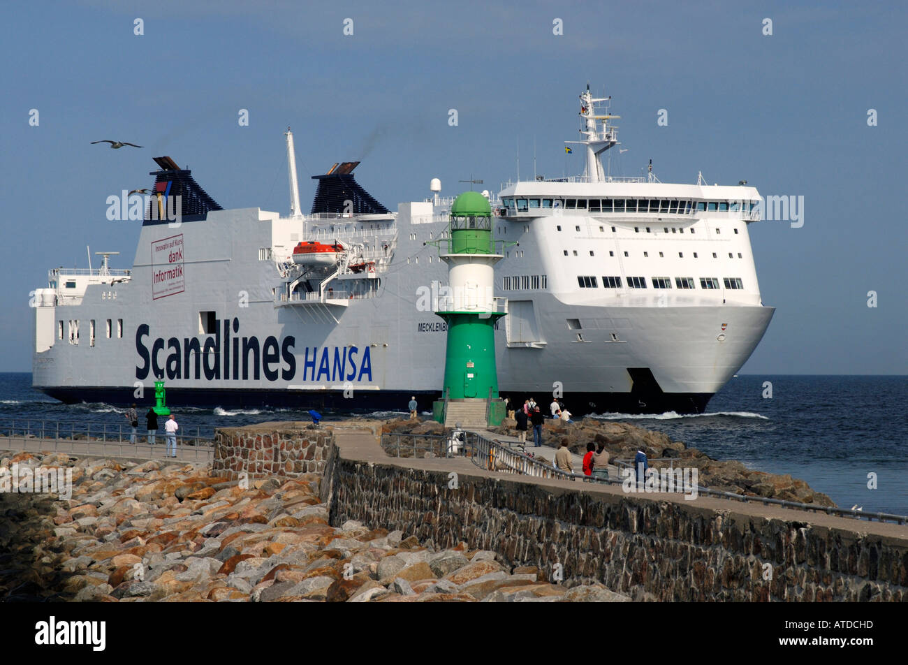 Una grande nave traghetto da Scandlines shipping company passa un faro all'entrata del porto di Warnemuende, Mecklenburg-Vorpommern Foto Stock