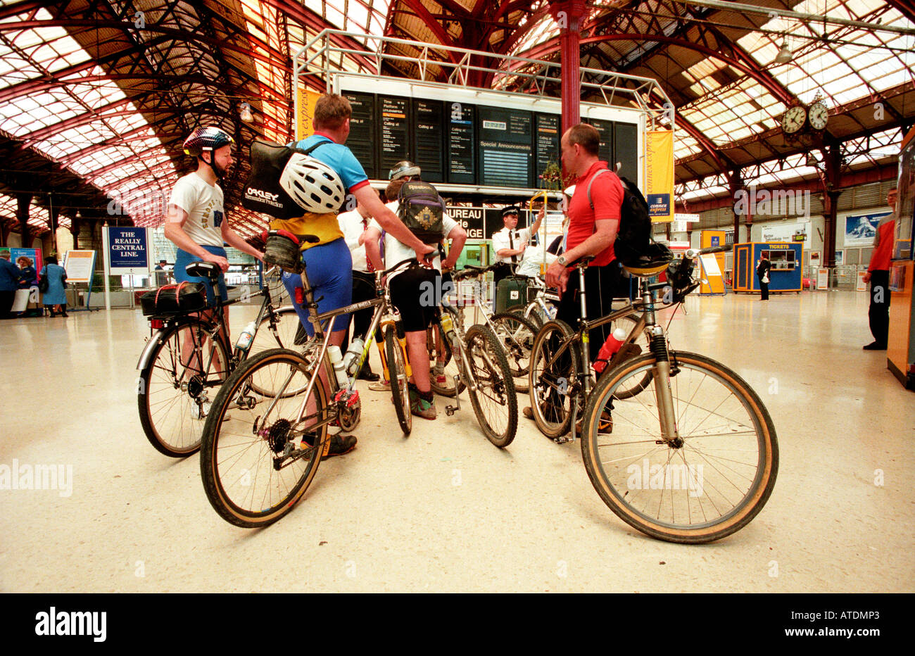 Quattro maschi i ciclisti dopo la Londra a Brighton in bicicletta in attesa alla stazione ferroviaria di Brighton per un treno home Foto Stock