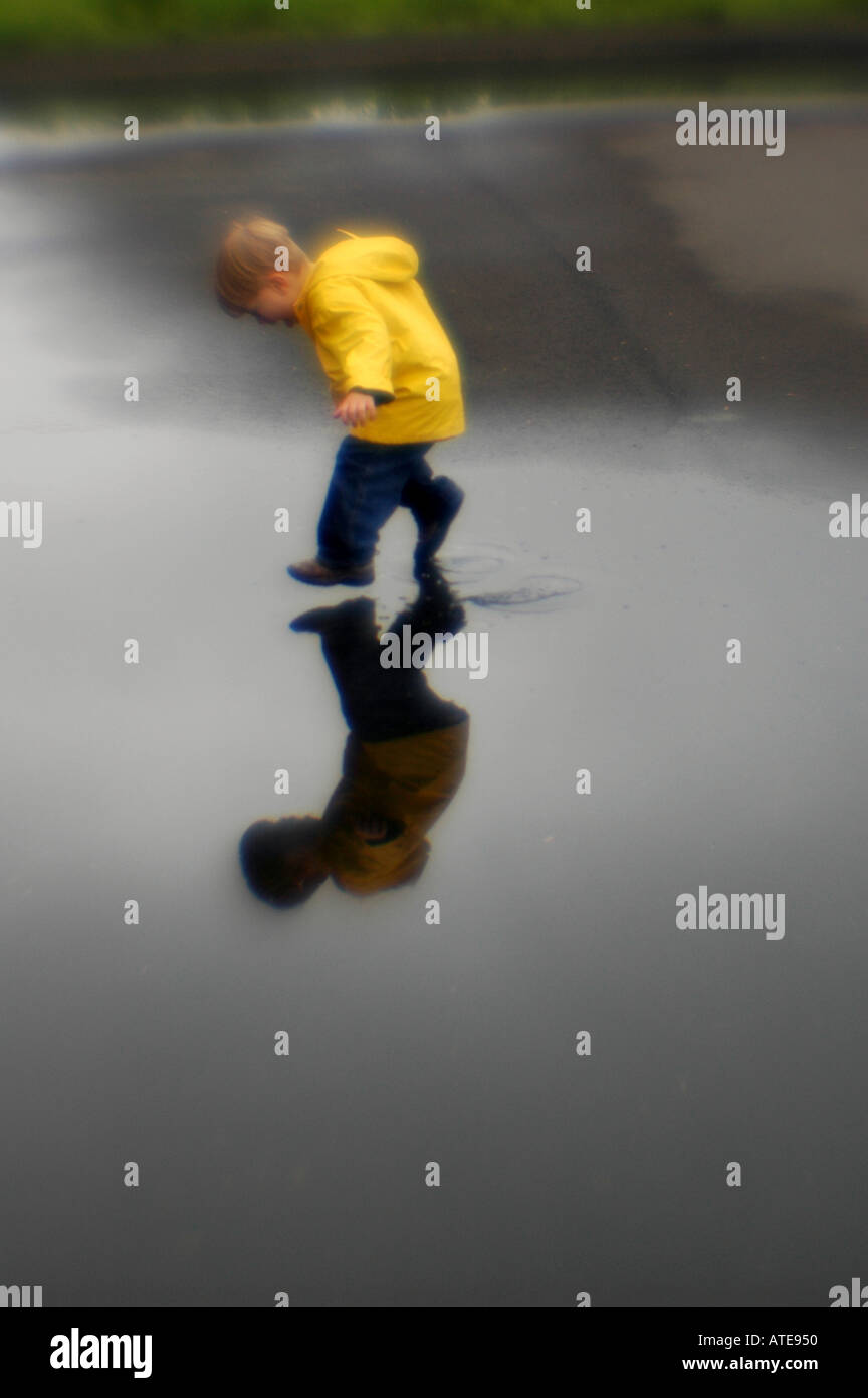 Piccolo ragazzo giocando in una pozza di acqua Foto Stock
