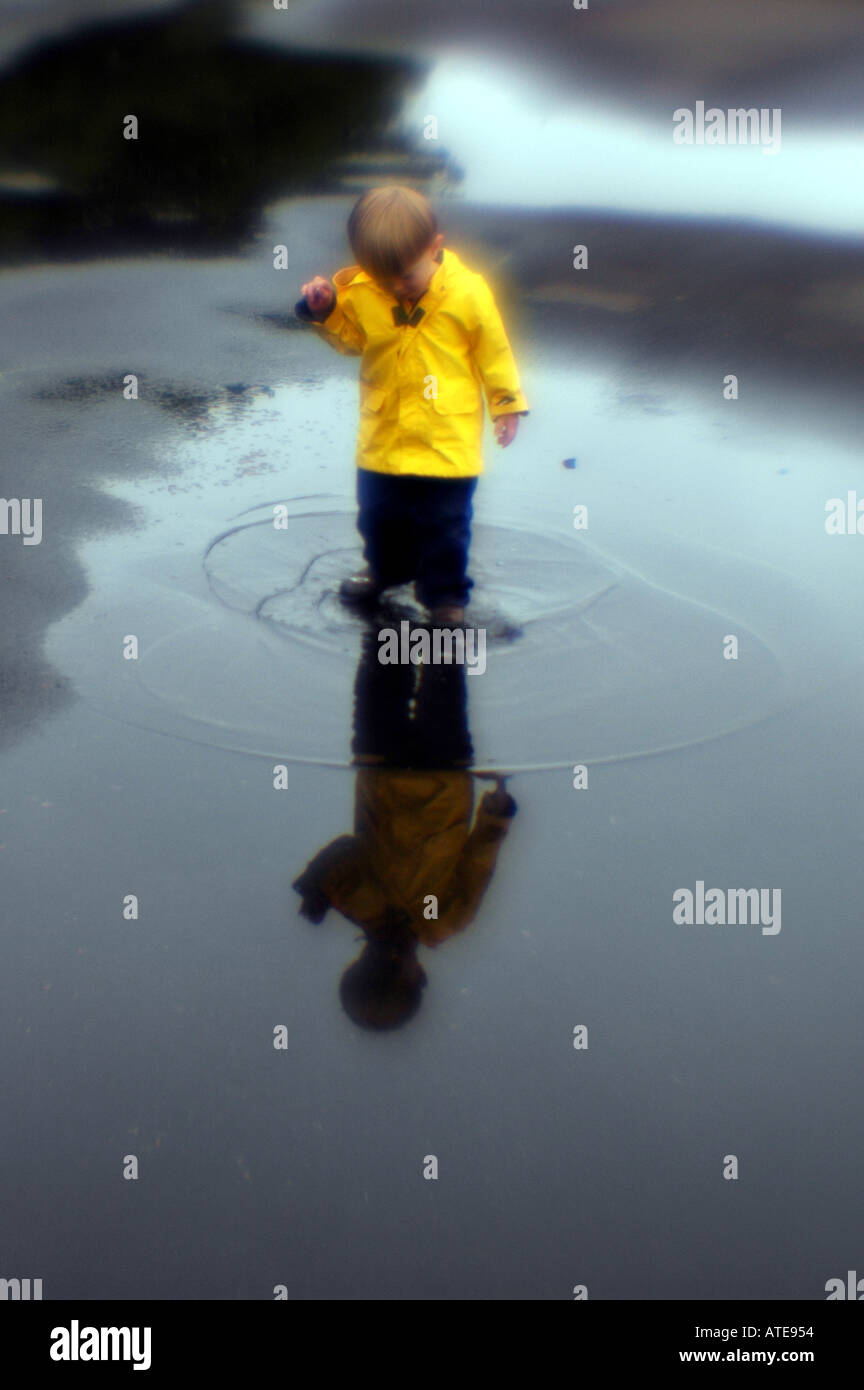 Piccolo ragazzo giocando in una pozza di acqua Foto Stock