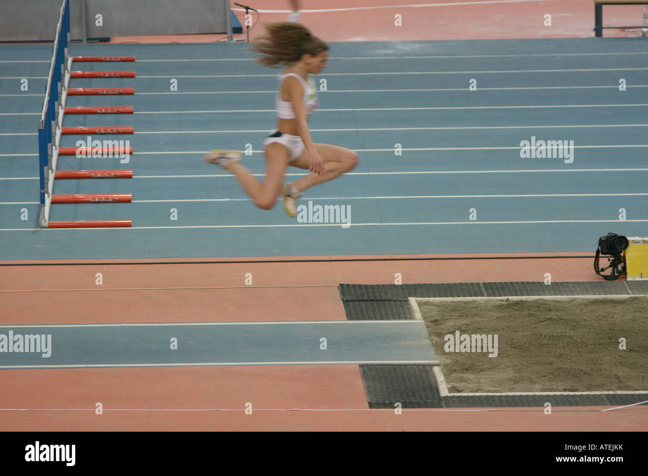 Donna atleta di eseguire la triplice salto in lungo su piste Foto Stock