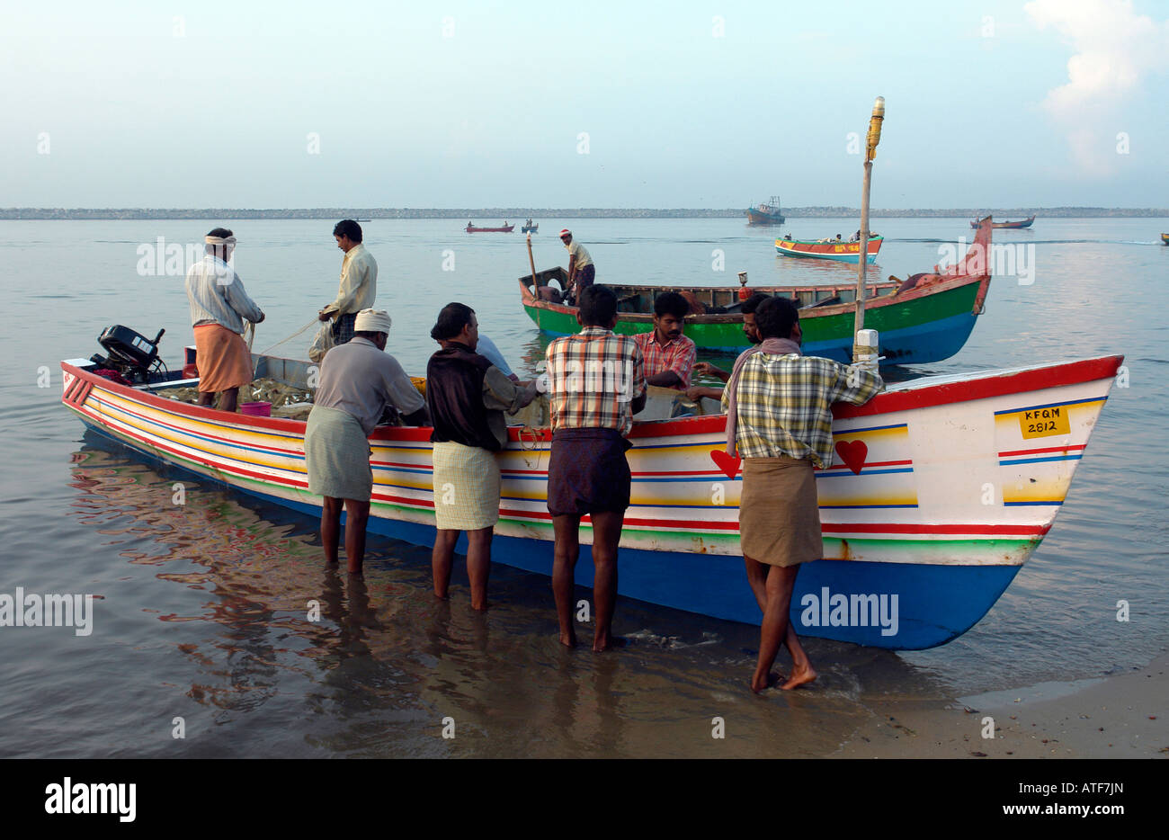 I pescatori locali e la tradizionale barca da pesca di controllare le loro reti in Quilon Foto Stock