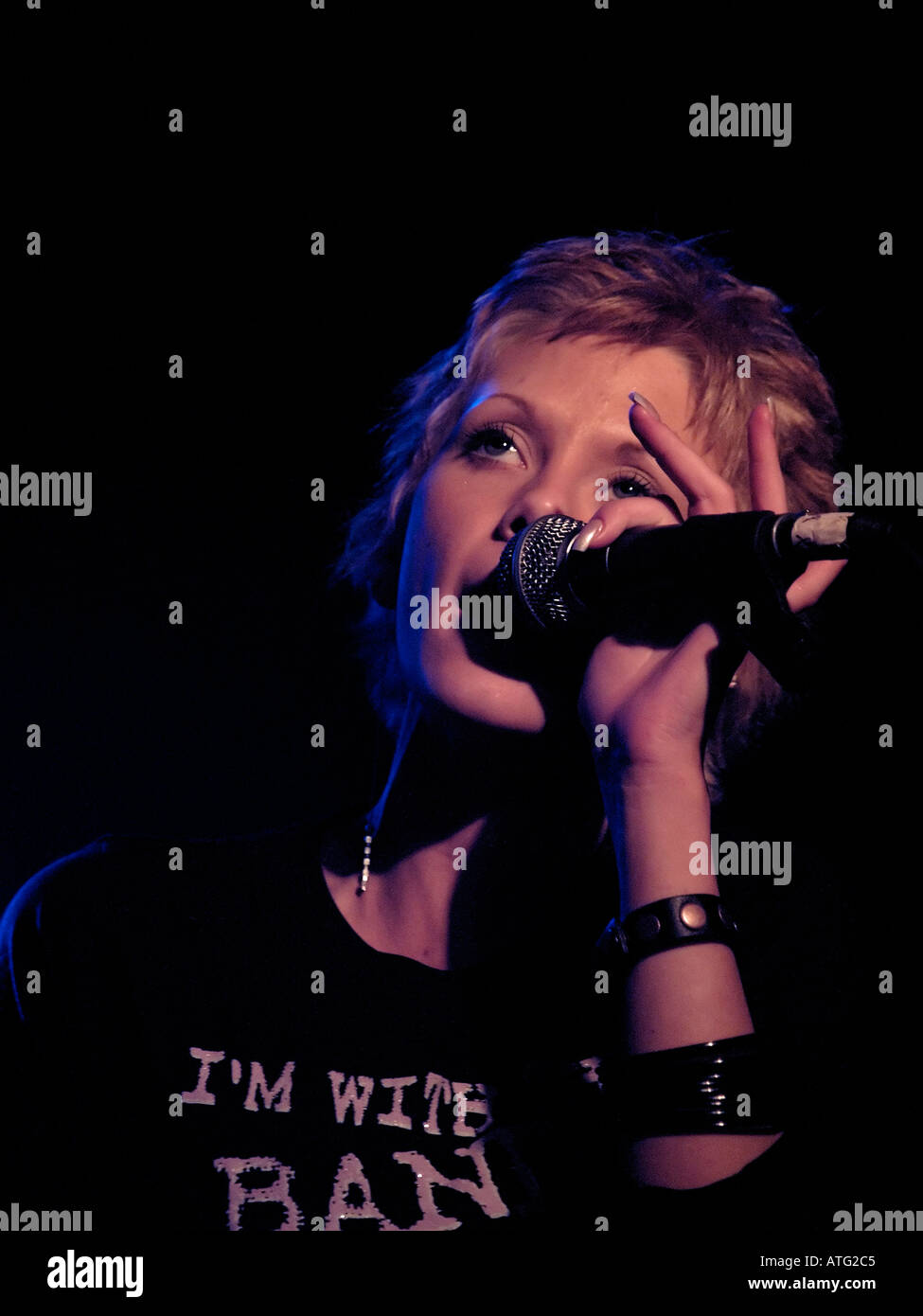 Cantante femminile sul palco nelle prestazioni con illuminazione colorata Foto Stock