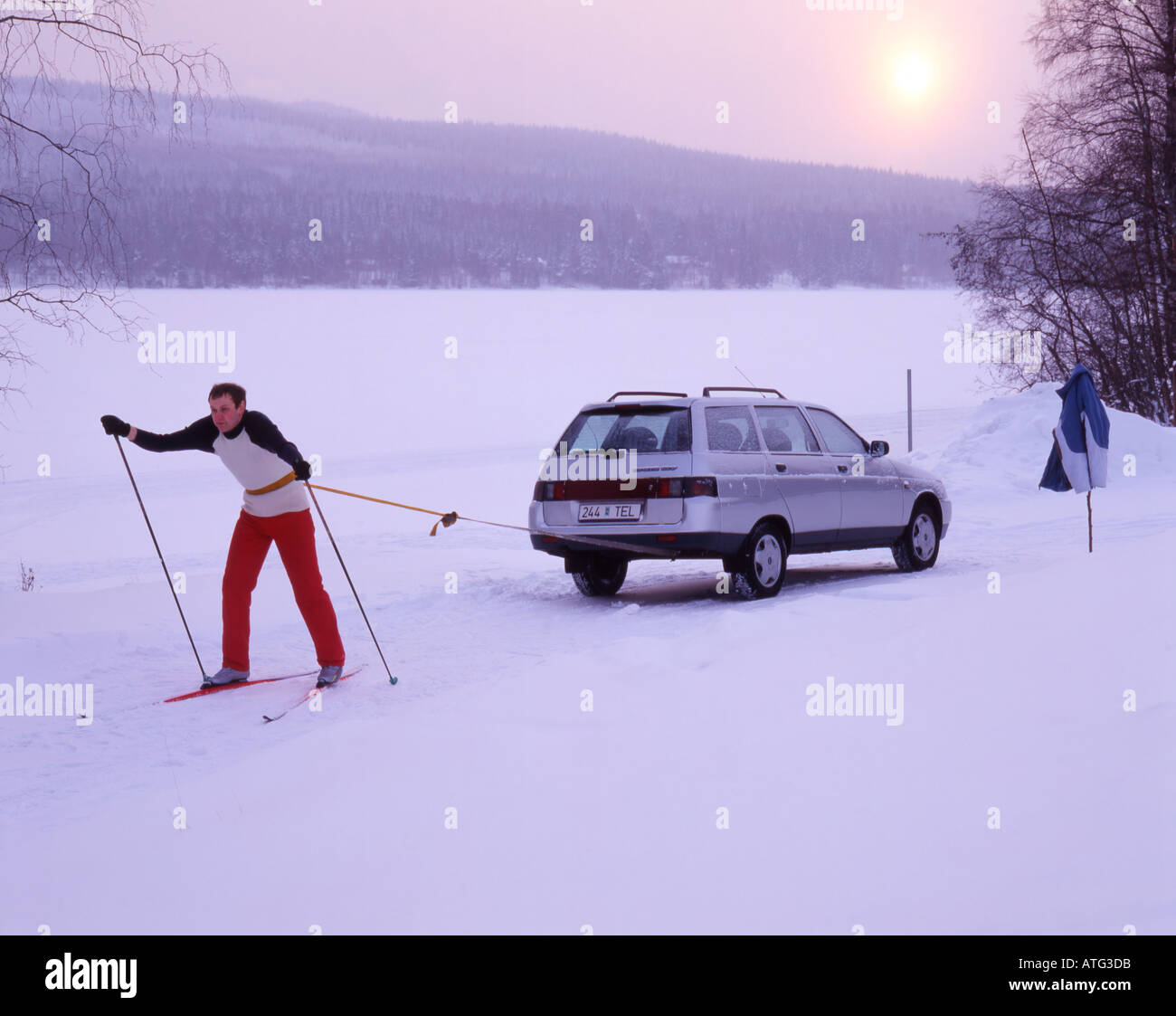 Sci uomo cercando di trainare la sua auto Foto Stock
