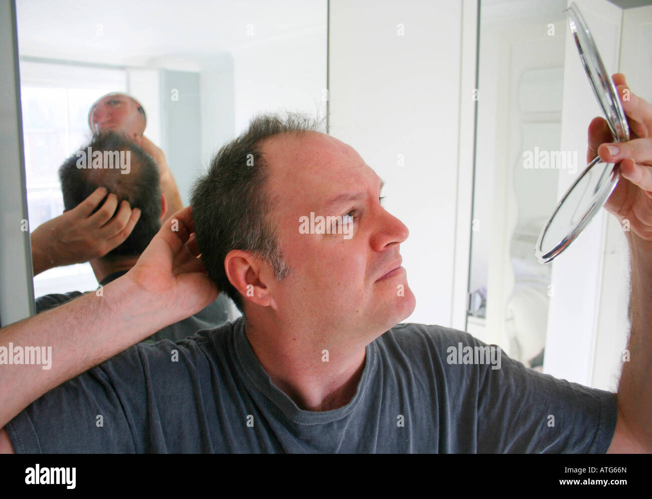 L'uomo controllo perdita di capelli in specchio Foto Stock