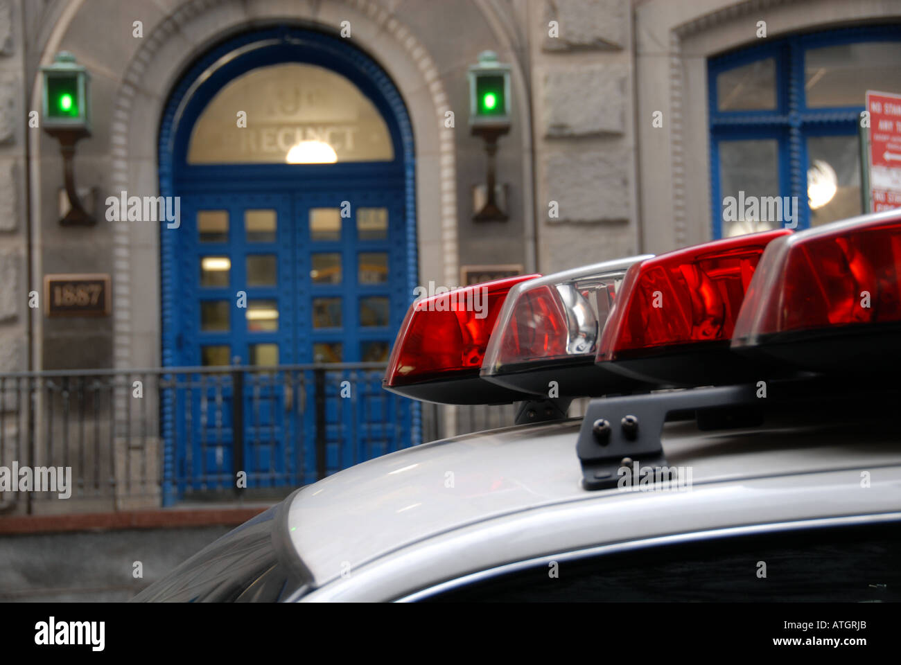 Luci sul tetto di una macchina della polizia parcheggiata di fronte un quartiere della stazione di polizia Foto Stock Luci sul tetto di una macchina della polizia parcheggiata di fronte un quartiere della stazione di polizia Foto Stock