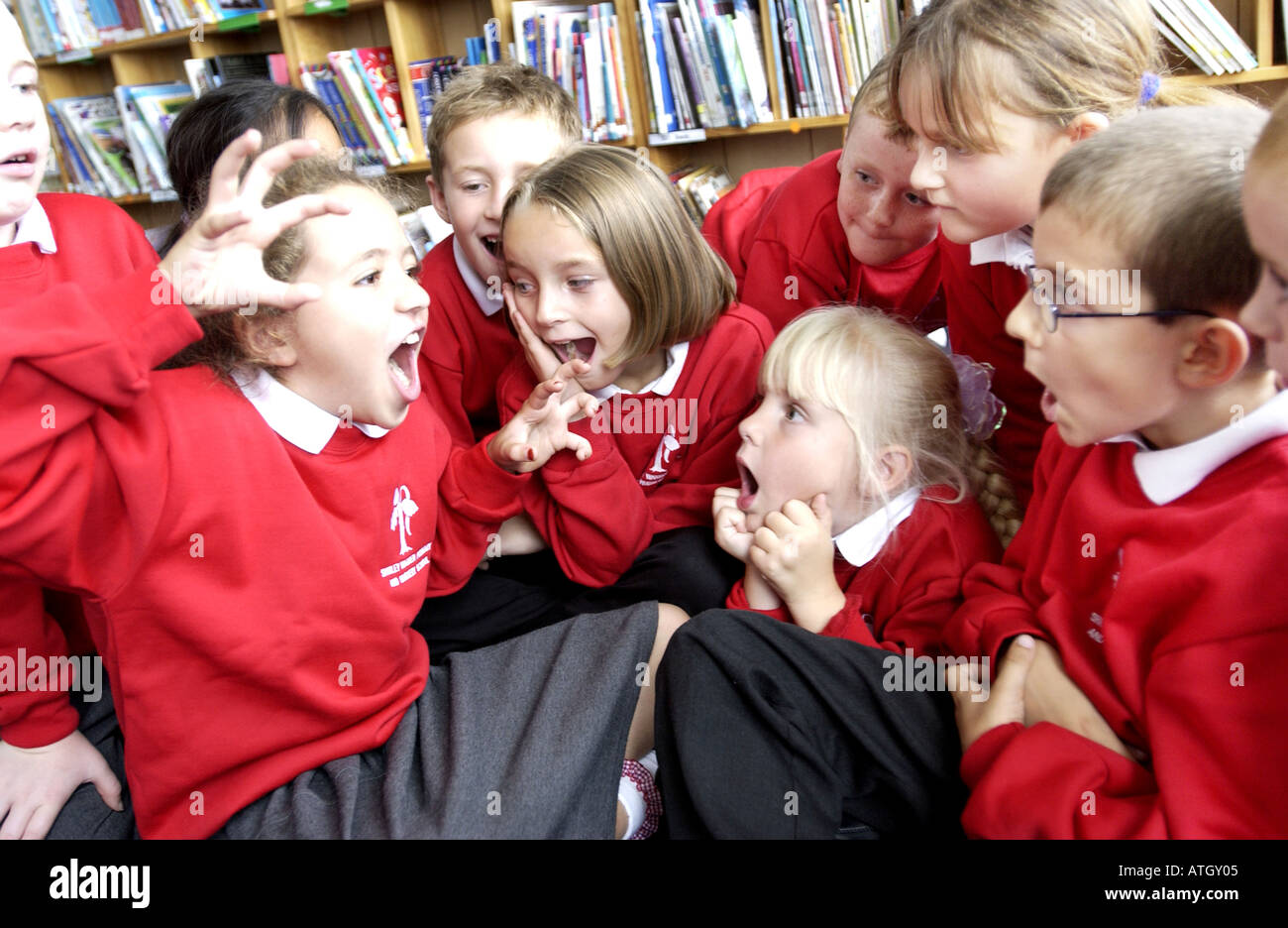 Avviso luminoso i ragazzi e le ragazze di interagire con glee in una scuola primaria storytelling classe Foto Stock