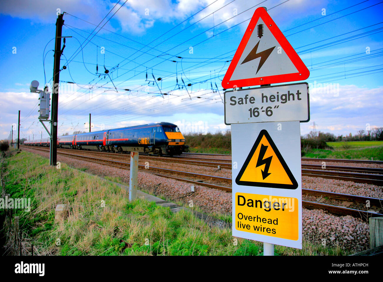 Energia elettrica ferroviaria avviso di pericolo segno a Lolham Peterborough linea ECM Inghilterra UK Europa ECML avvicinando 82 treno di classe Foto Stock