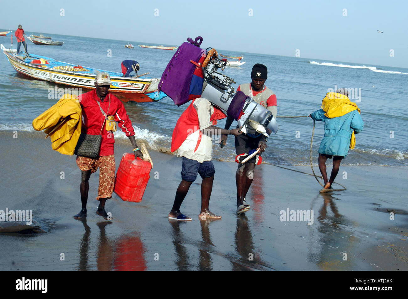 Tanji villaggio di pescatori sulla costa atlantica della Gambia. Gli uomini rimuovere i motori fuoribordo e le attrezzature dalle barche. Foto Stock