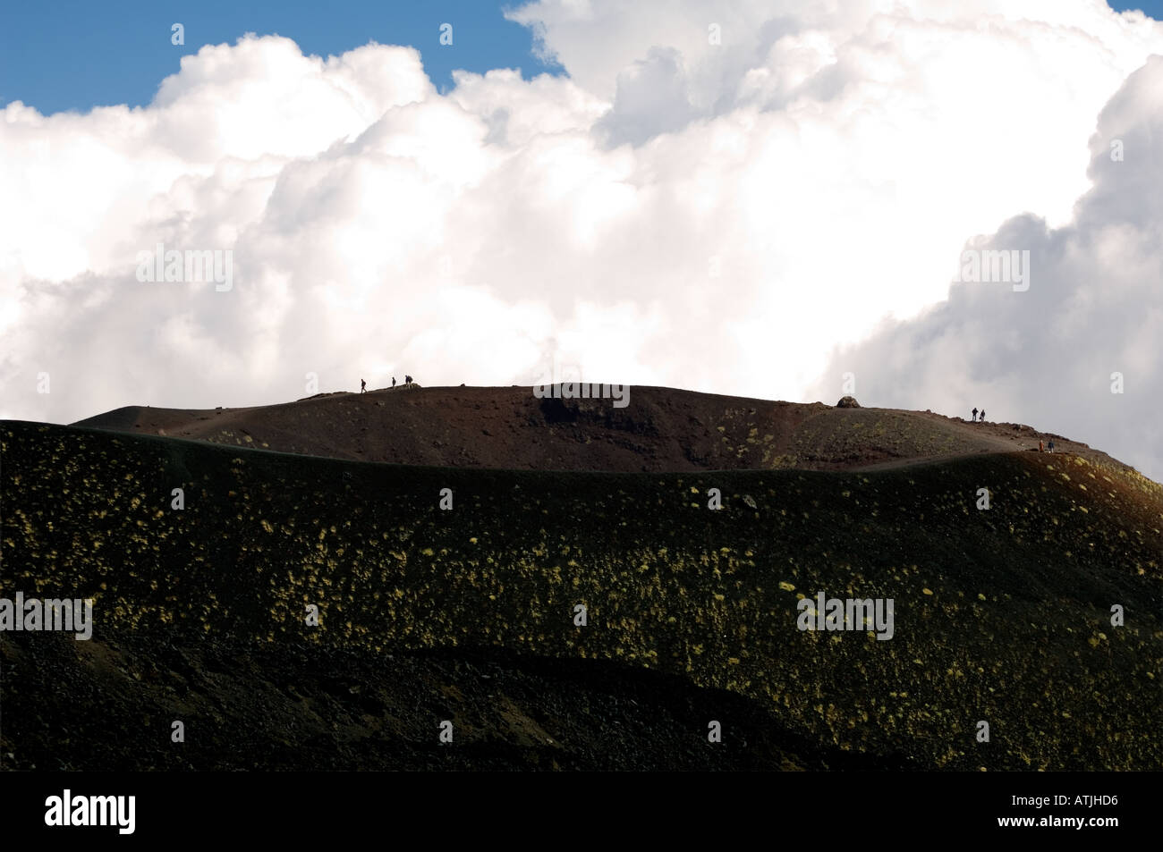 Piccole figure umane esposto contro le nuvole sul bordo di un piccolo cratere laterale di cenere nera sul Monte Etna Sicilia Foto Stock