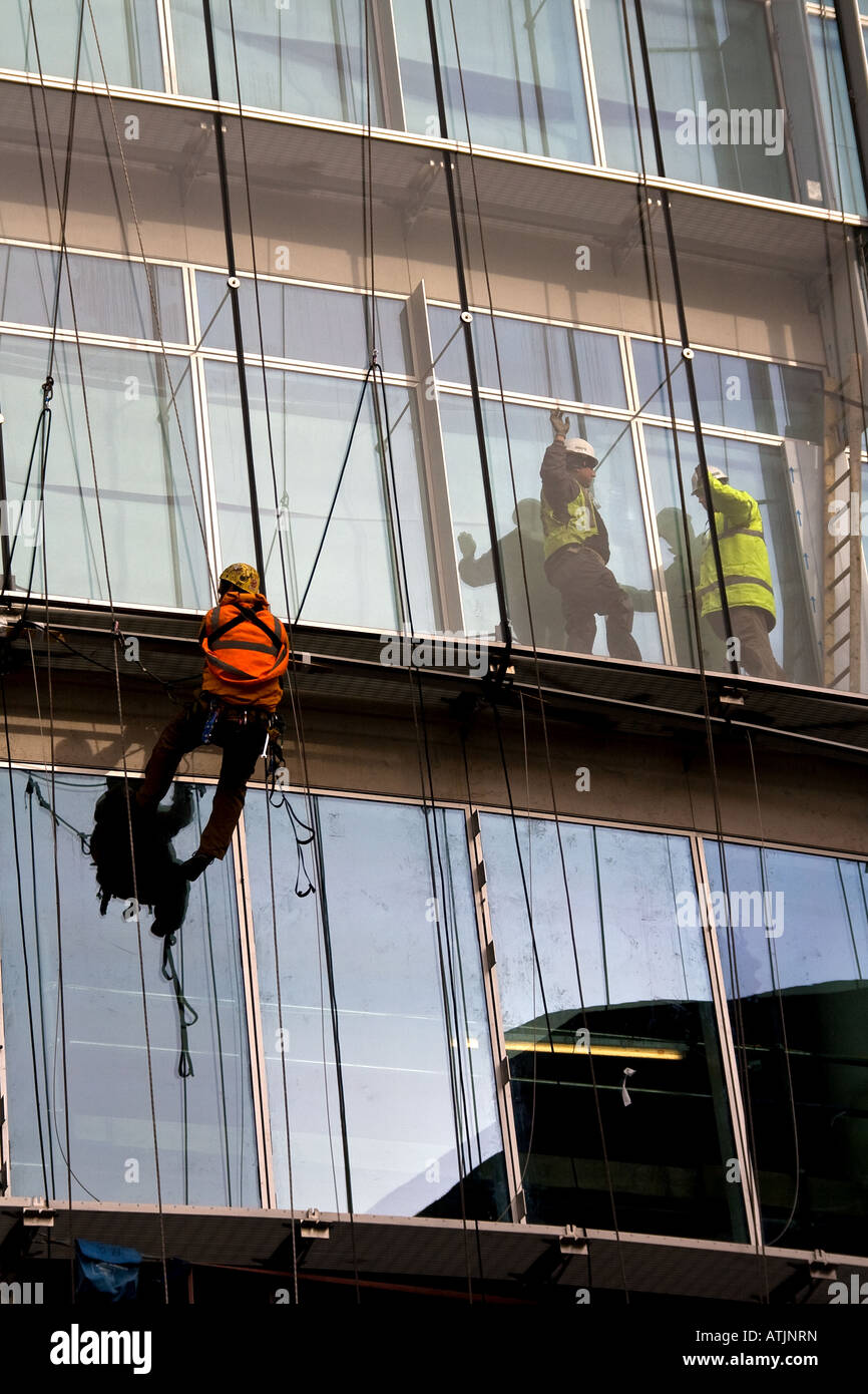 Operai che lavorano sul lato del grande edificio, LONDON REGNO UNITO Foto Stock