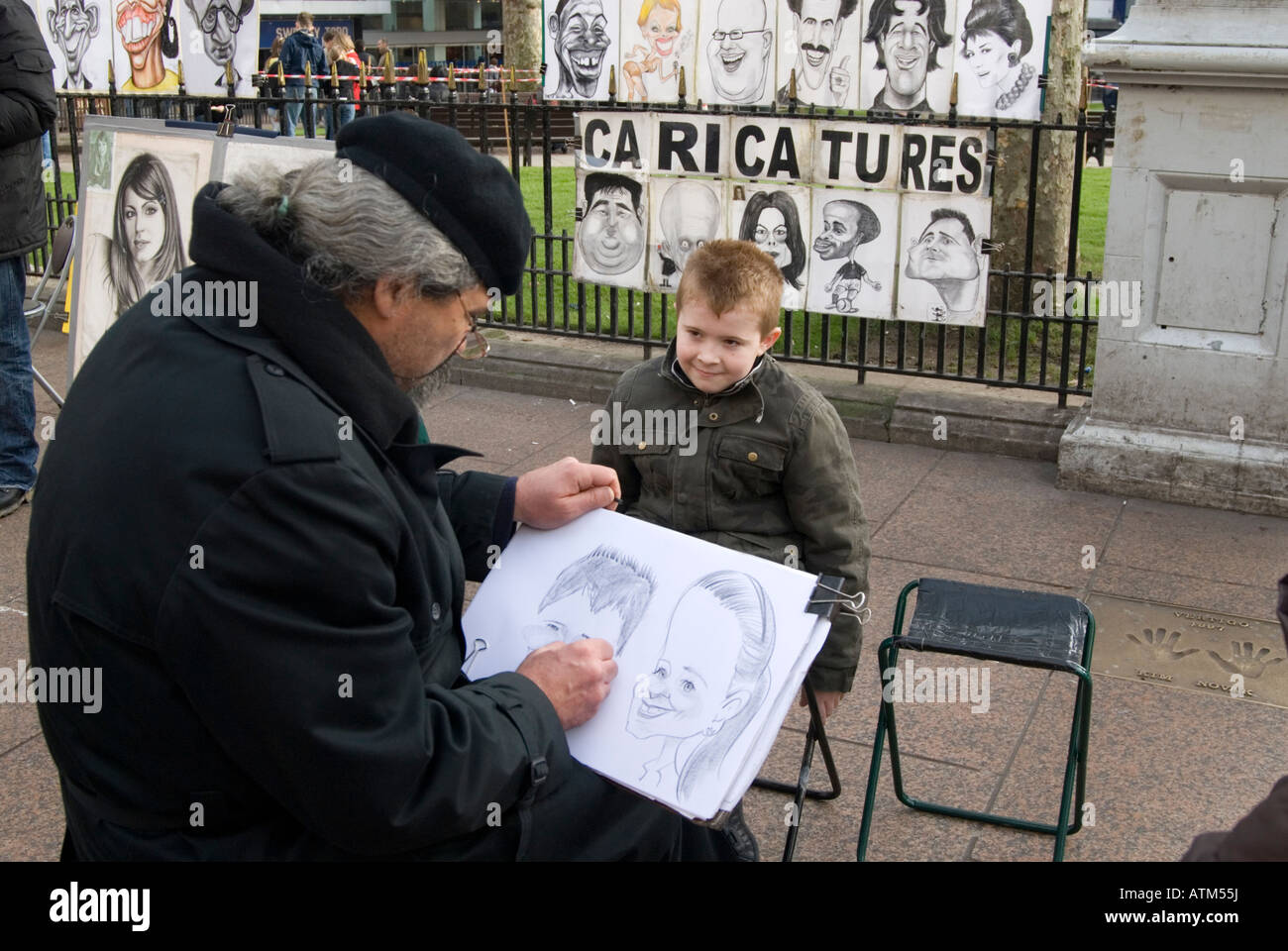 Artista di strada che disegna una caricatura di un ragazzino a Leicester Square, Londra, Regno Unito Foto Stock