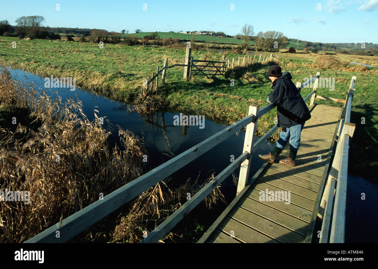 Donna sul ponte sul canale di drenaggio Coombe Haven valley Hastings Bexhill EAST SUSSEX REGNO UNITO Inghilterra Europa Foto Stock