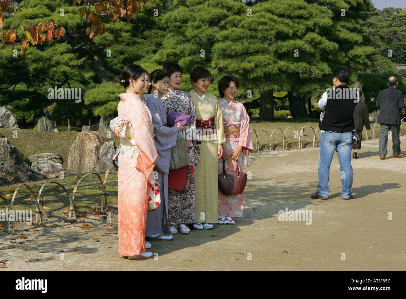 Un gruppo di donne giapponesi indossando il tradizionale kimono posano per una fotografia di fronte ai giardini presso il castello di Nijo a Kyoto in Giappone Foto Stock