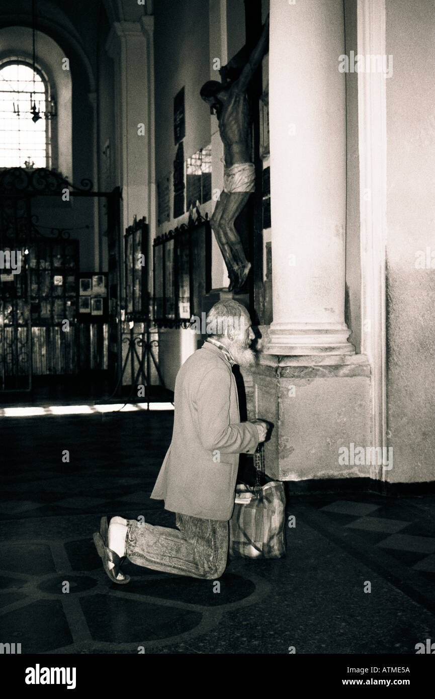 Il vecchio uomo inginocchiato in chiesa in preghiera in Europa orientale Foto Stock