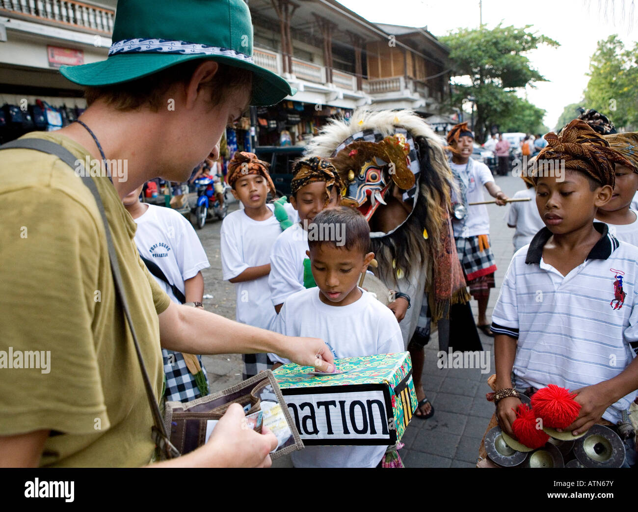 Tourist una donazione in locale i ragazzi Balinese durante il Festival di Kuningan Ubud Bali Indonesia Foto Stock